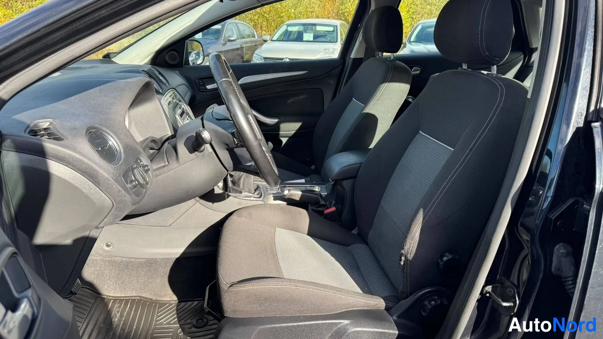 Muu: Mustan Ford Mondeon etuistuimet kankaalla penkkien ja kojelaudan näkyessä avatun ovista.