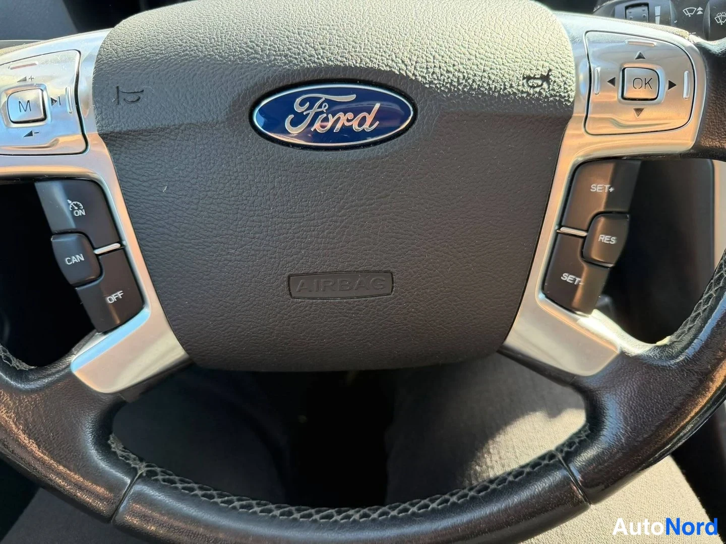 Yksityiskohta: Ohjauspyörän keskiosa Ford-merkillä ja AIRBAG-tekstillä; vasemmalla painikkeet CAN ja OFF, oikealla SET+, RES ja SET.