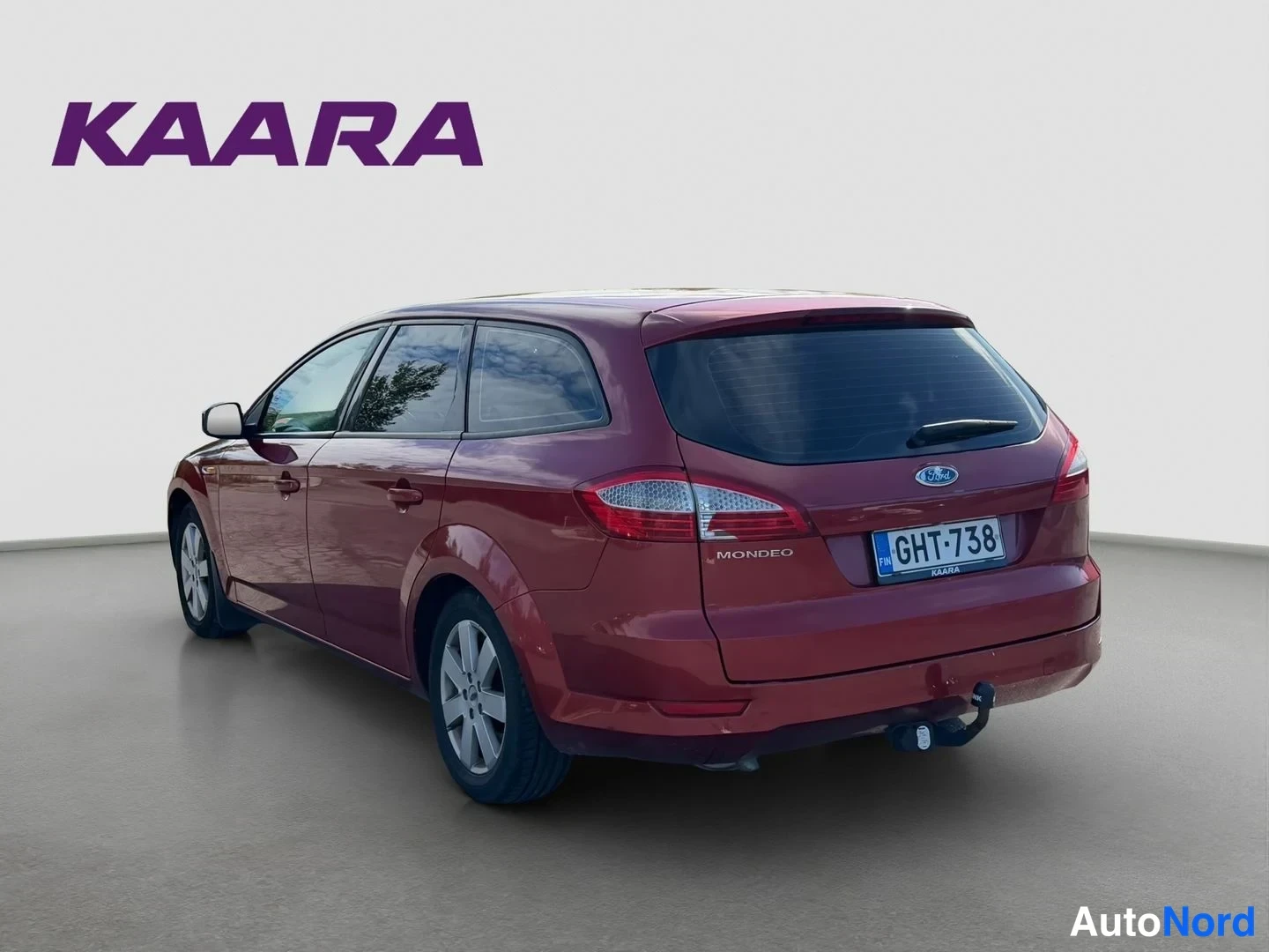 Takaviisto: Punainen Ford Mondeofarmarina takaa kulmasta: rekisteritunnus, takavalo ja Mondeo-teksti näkyvät, perässä vetokoukku.