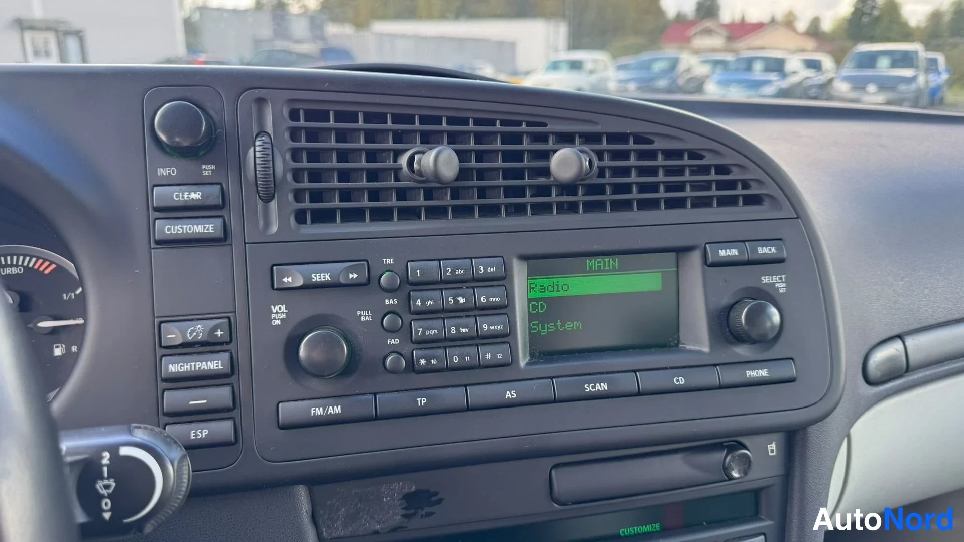 Muu: Auton keskikonsolin radio- ja viihdejärjestelmä; näytössä MAIN, Radio, CD ja System, näppäimistö ja FM/AM-, TP-, AS-, SCAN-, CD- ja PHONE-napit.