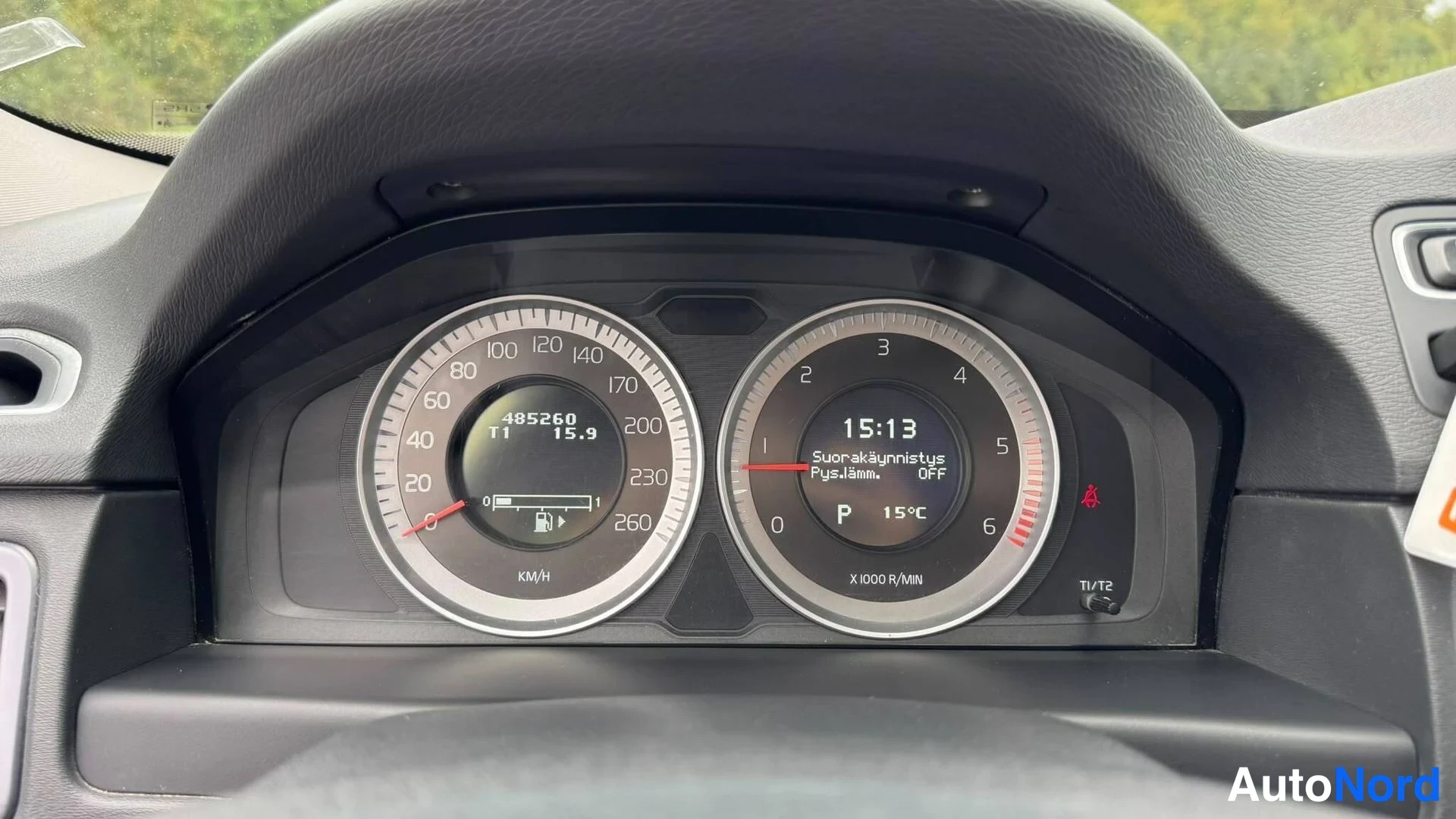 Takaa: Kojelaudan mittaristo: nopeusmittari näyttää 485260 km, polttoainemittari, kello 15:13 ja lämpötila 15 °C.