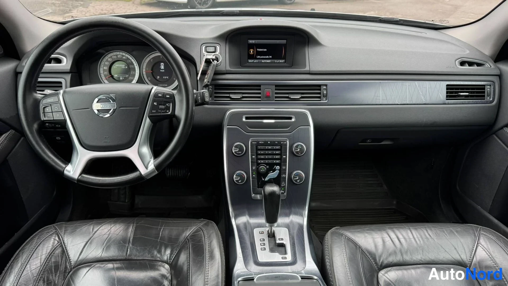 Takaa: Volvo-ohjauspyörä, hallintapaneeli, keskikonsoli ja vaihtajan monotone.