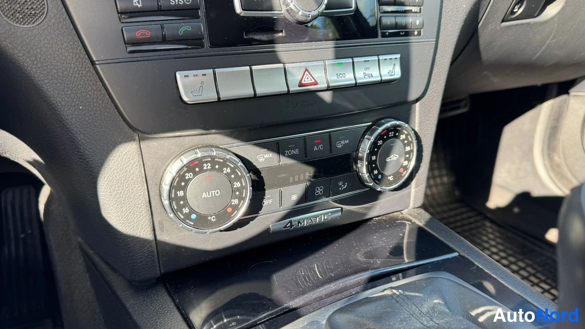 Muu: Ilmastoinnin säätimet kahdella kierrepainikkeella, AUTO-näytöllä ja 4MATIC-kyltillä keskikonsolissa.