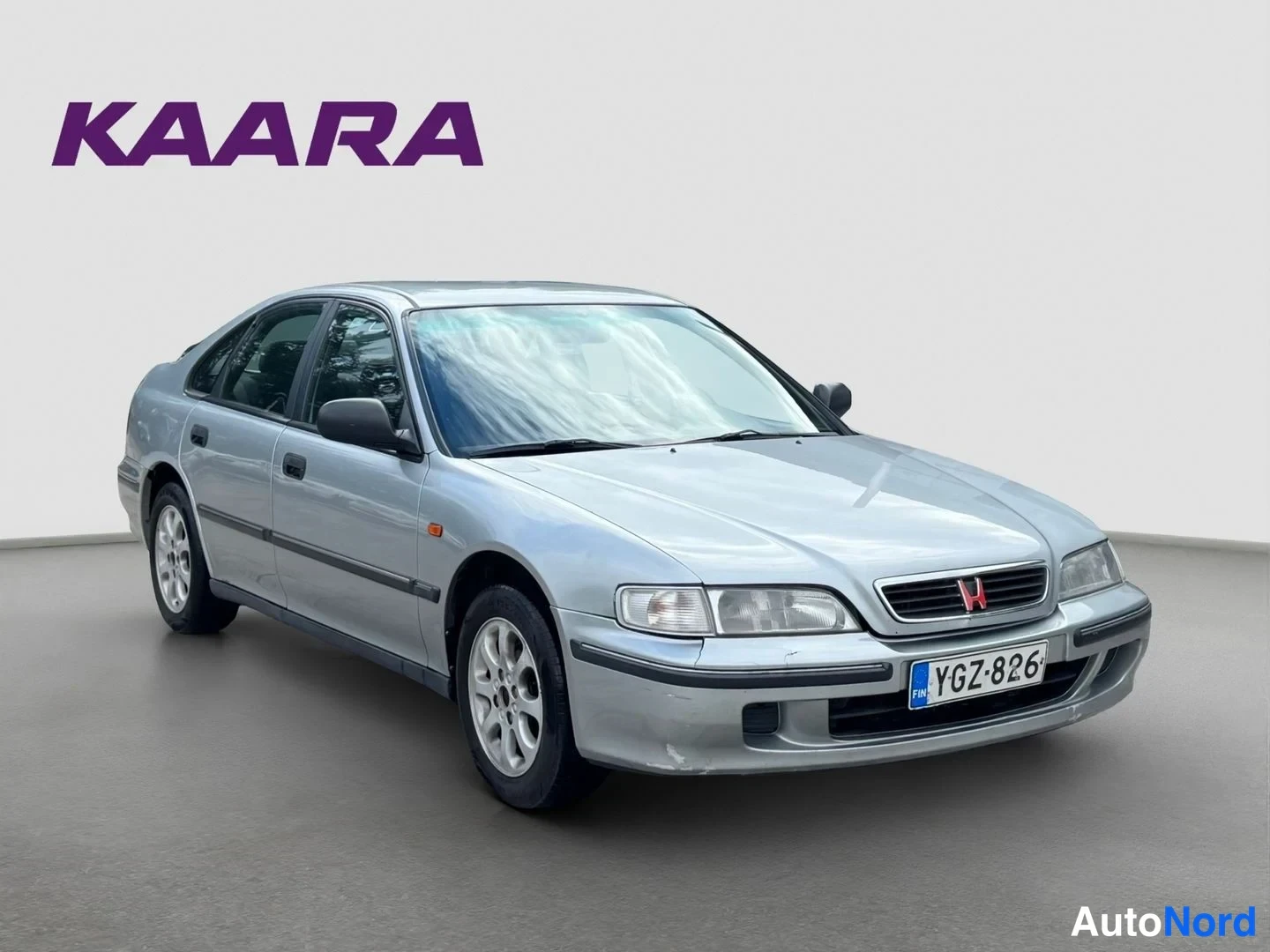 Etuviisto, nokka oikealle: Hopeinen Honda Accord -sedan kulmaetuvasivulta oikeaan suuntaan, rekisteritunnus.