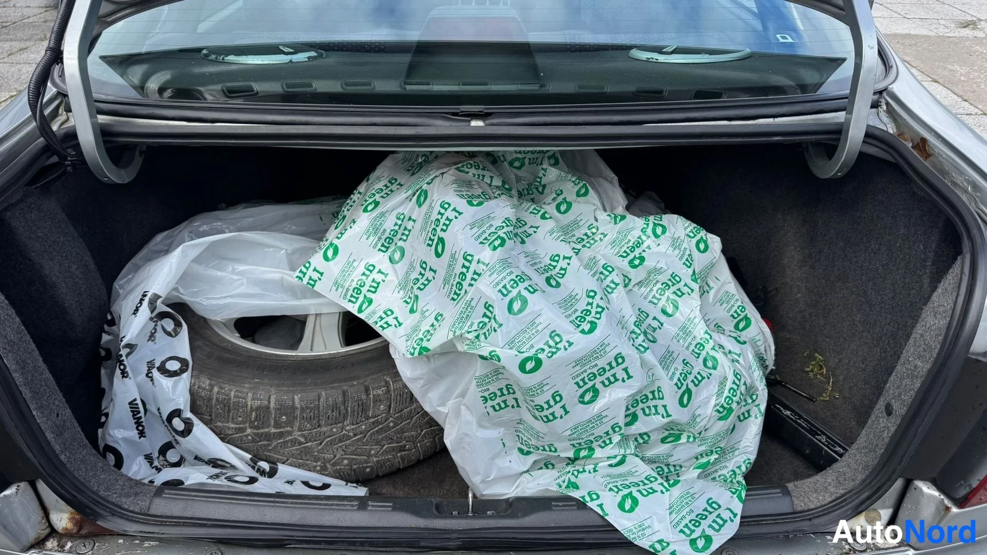 Muu: Avoin tavaratila: mahtuu vararengas vanteen ja rengusivun 4x4 merkinnällä, musta matto, osa auton alustasta ja reunusten ruostepisteet.
