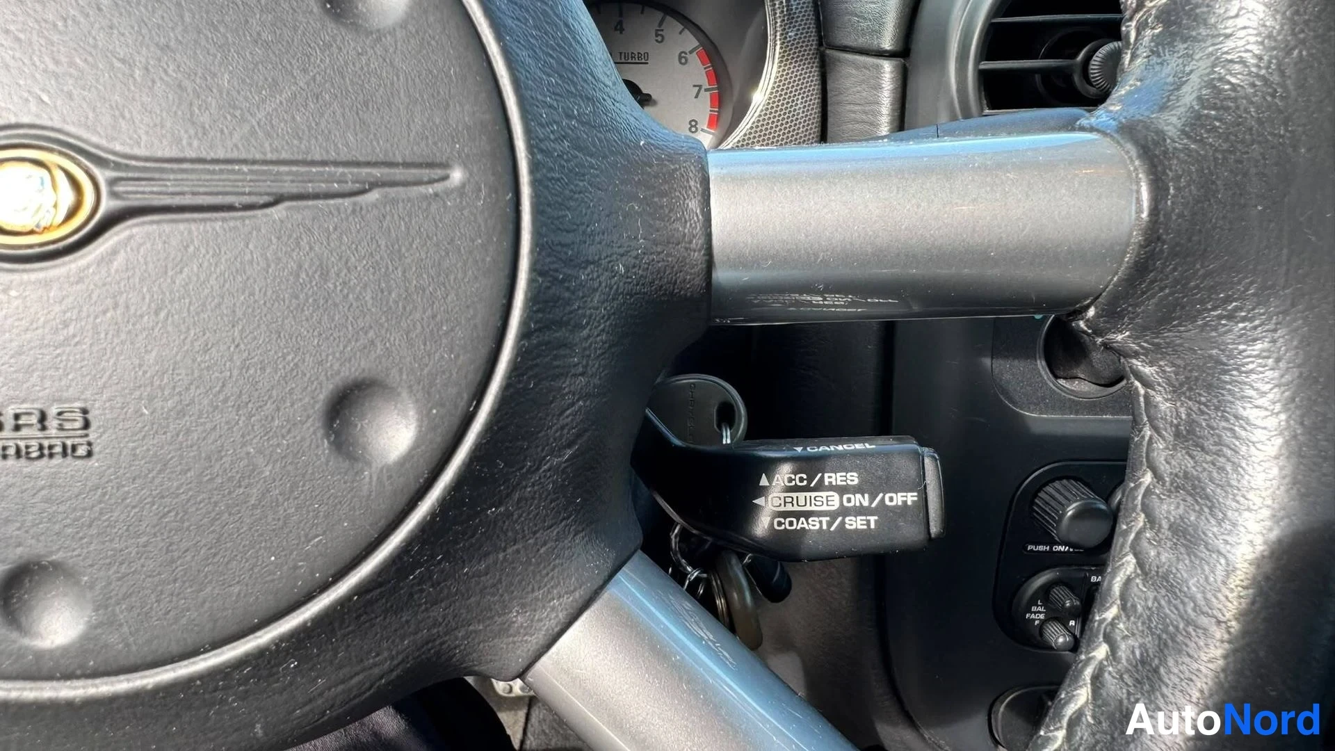 Muu: Ohjauspyörän Chrysler-merkki, ratti, virta-avain ja vakionopeudensäädinvarsi ('CRUISE ON/OFF'), takana nopeusmittari 'TURBO'.