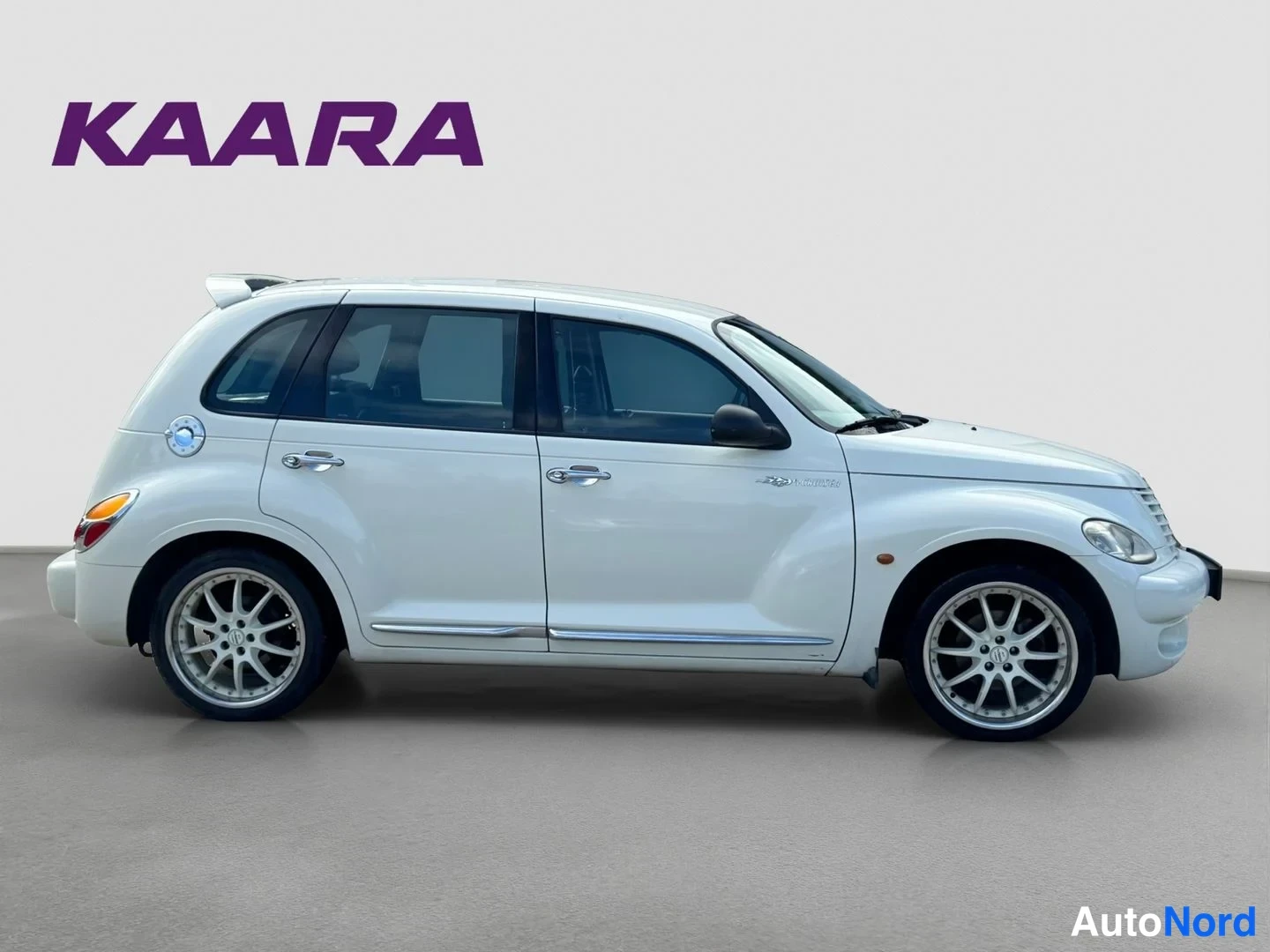 Sivulta: Valkoinen Chrysler PT Cruiser sivusta, oikea kylki kuvattuna