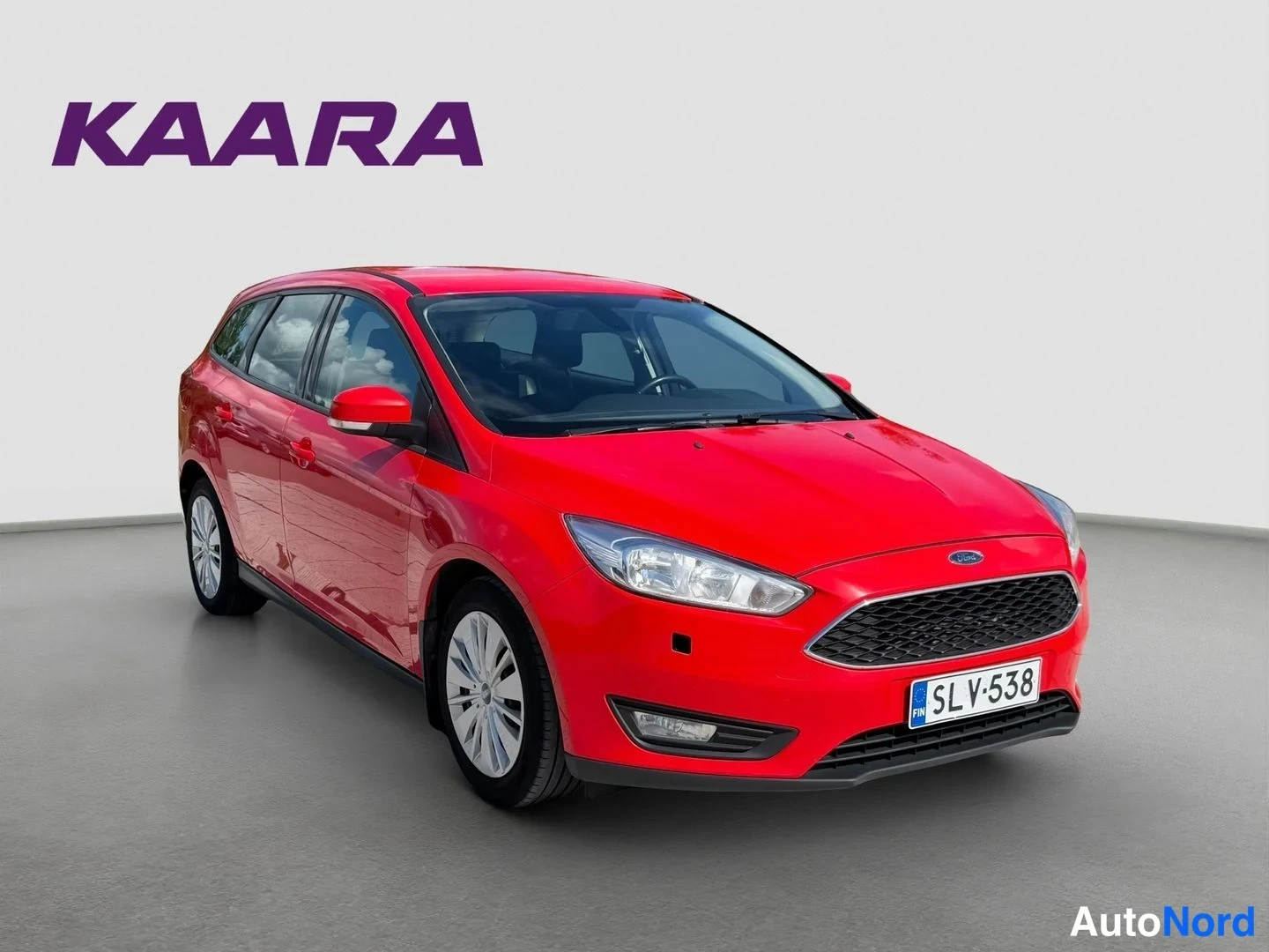 Etuviisto, nokka oikealle: Ford Focus -asema-auton punainen etukulmanäkymä toisesta suunnasta, rekisteritunnus.