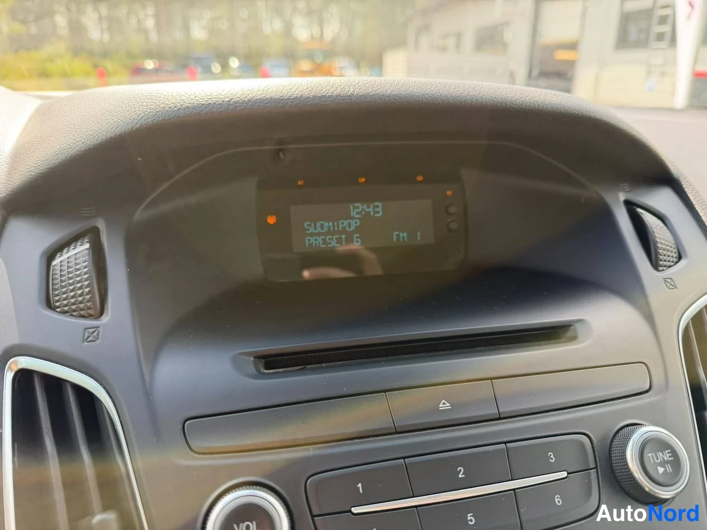 Takaa: Kojeiston radioyksikön näyttö näyttää kellonajan 12:43, teksti SUOMIPOP ja PRESET 6, FM 1.