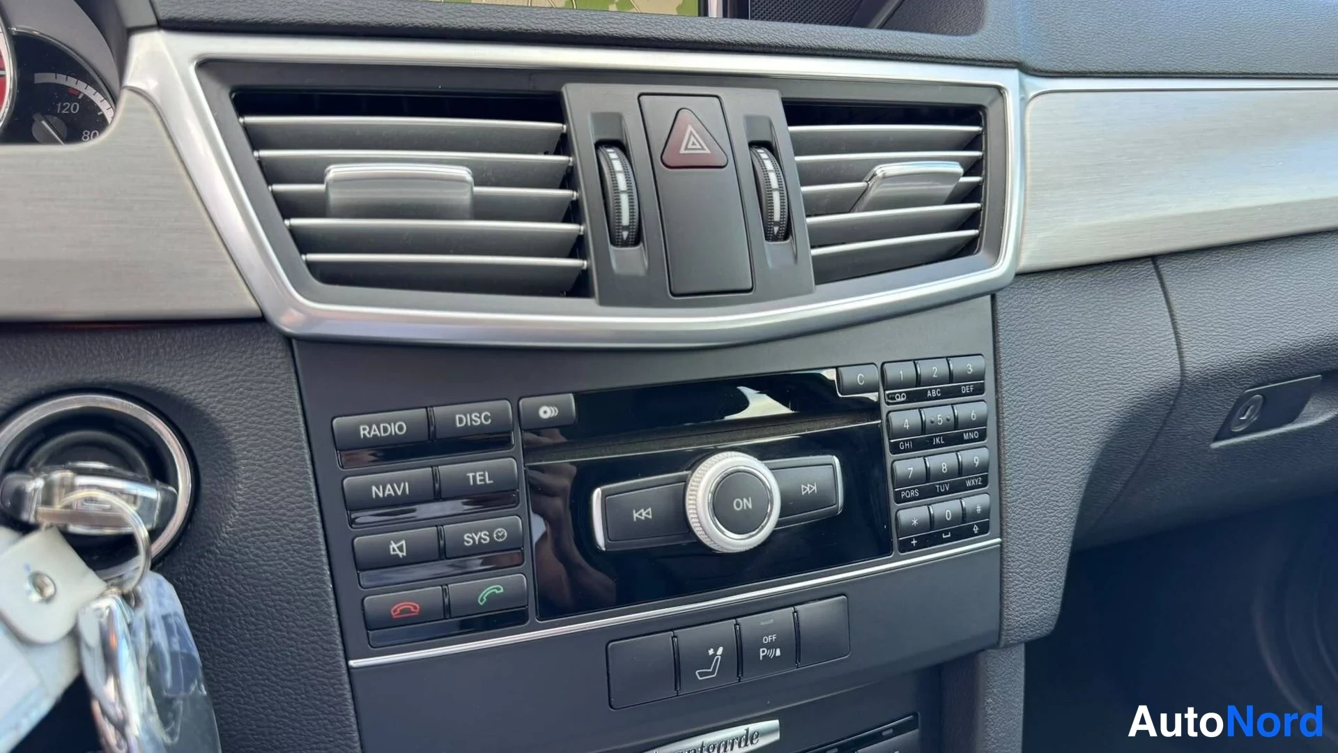 Muu: Keskikonsolin radiopaneeli painikkeilla RADIO, DISC, NAVI, TEL ja SYS, numeronäppäimistö sekä varoituskolmiopainike.