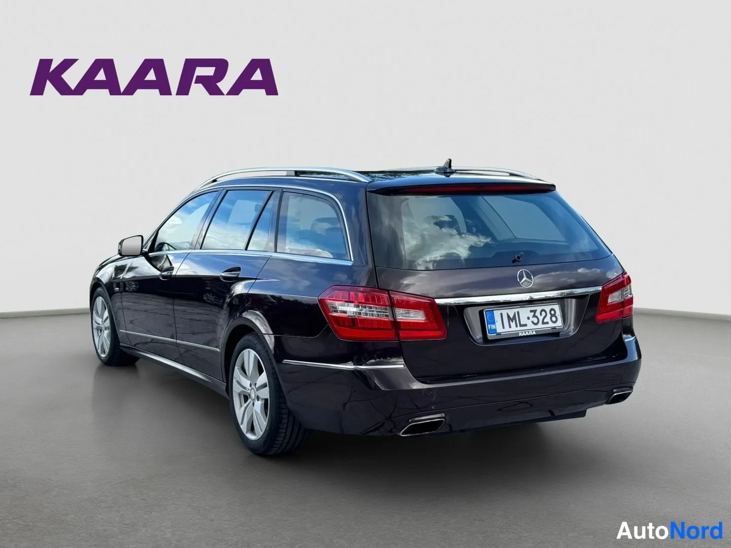 Takaviisto: Auton takakolmasosakuva: tumma farmariauto, rekisterikilpi, Mercedes-tähti takaluukussa ja kattotelineet.