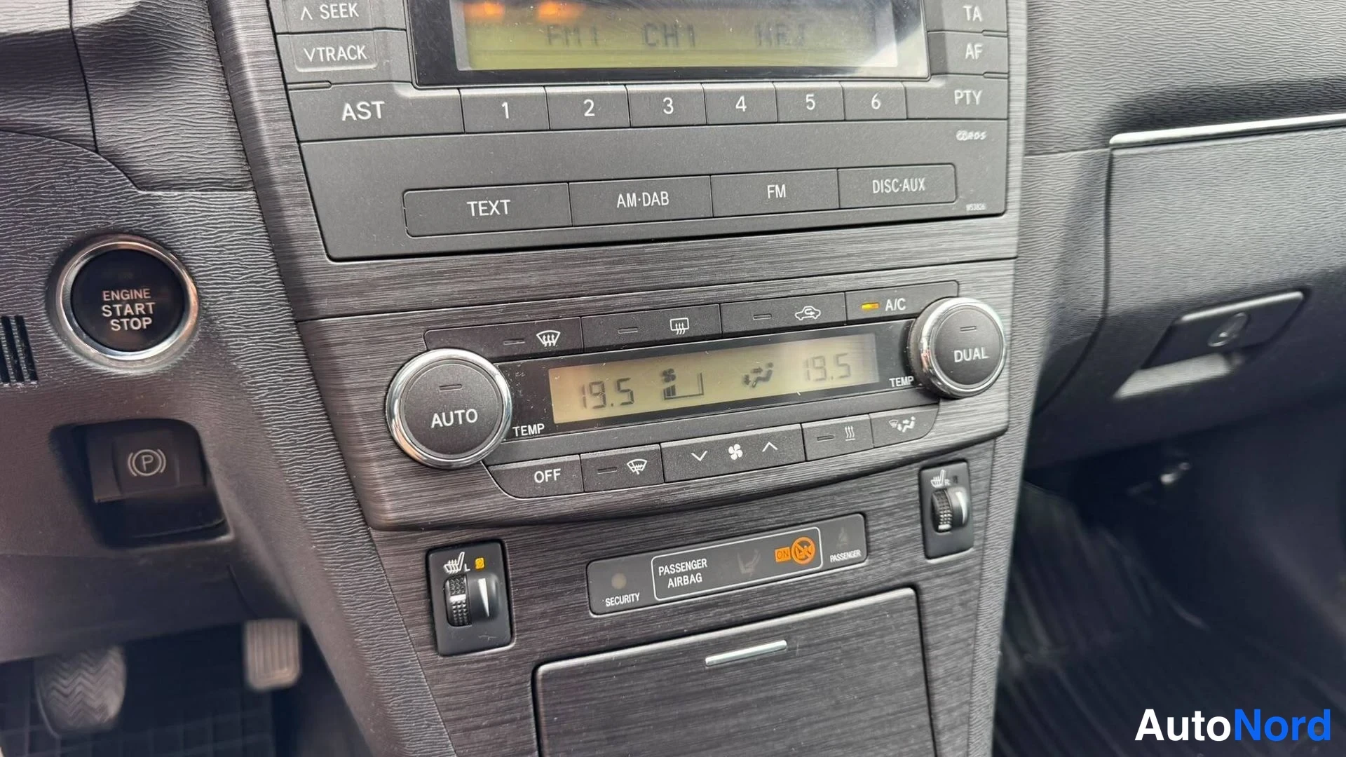 Muu: Keskihallin alaosa: ilmastointipaneeli AUTO-, A/C- ja DUAL-painikkeilla, näytössä arvot 19,5, ENGINE START STOP -painike, (P)-painike sekä PASSENGER AIRBAG -eti