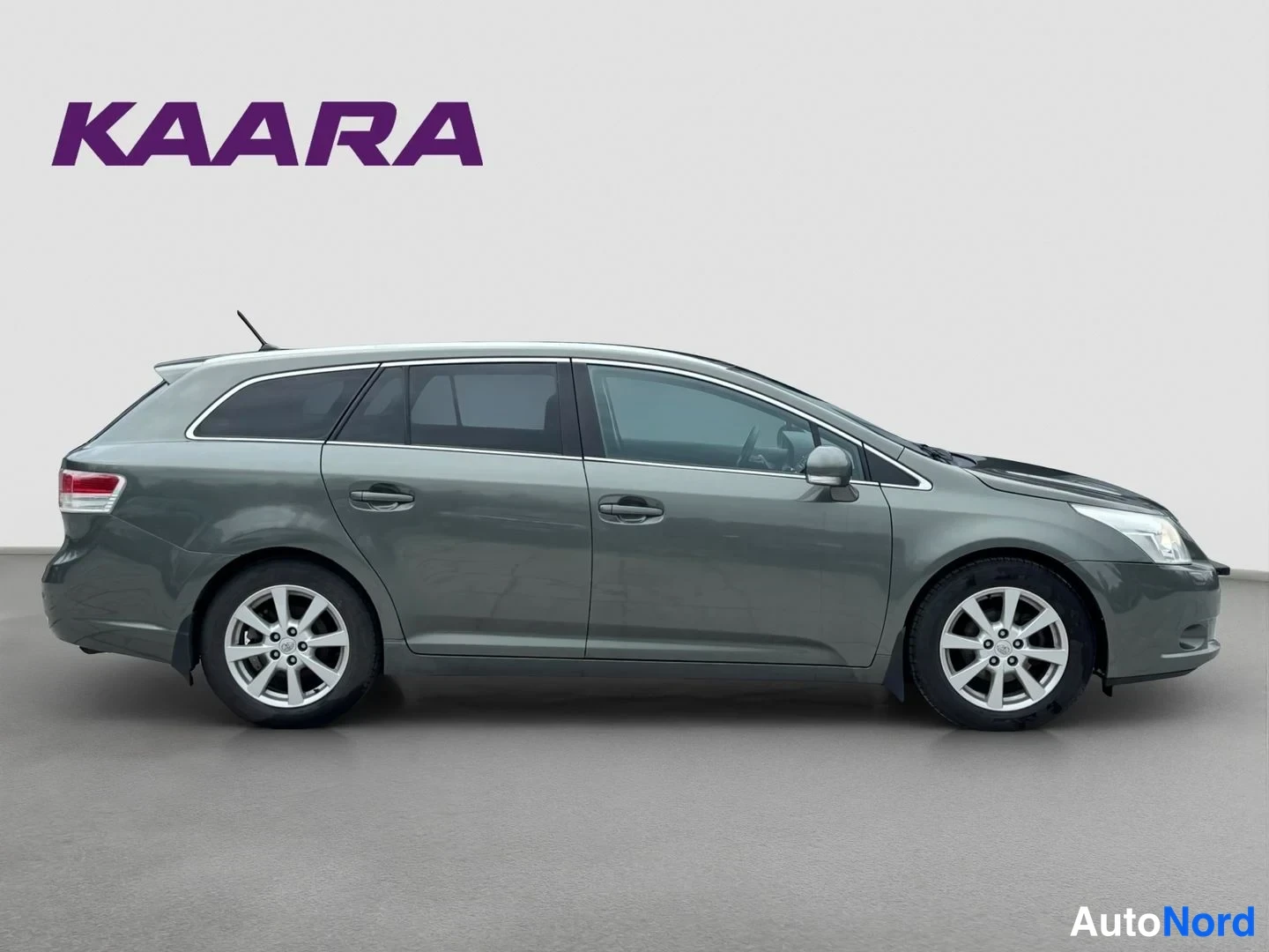 Takaviisto: Tummanharmaa Toyota Avensis -farmari sivulta oikealta.