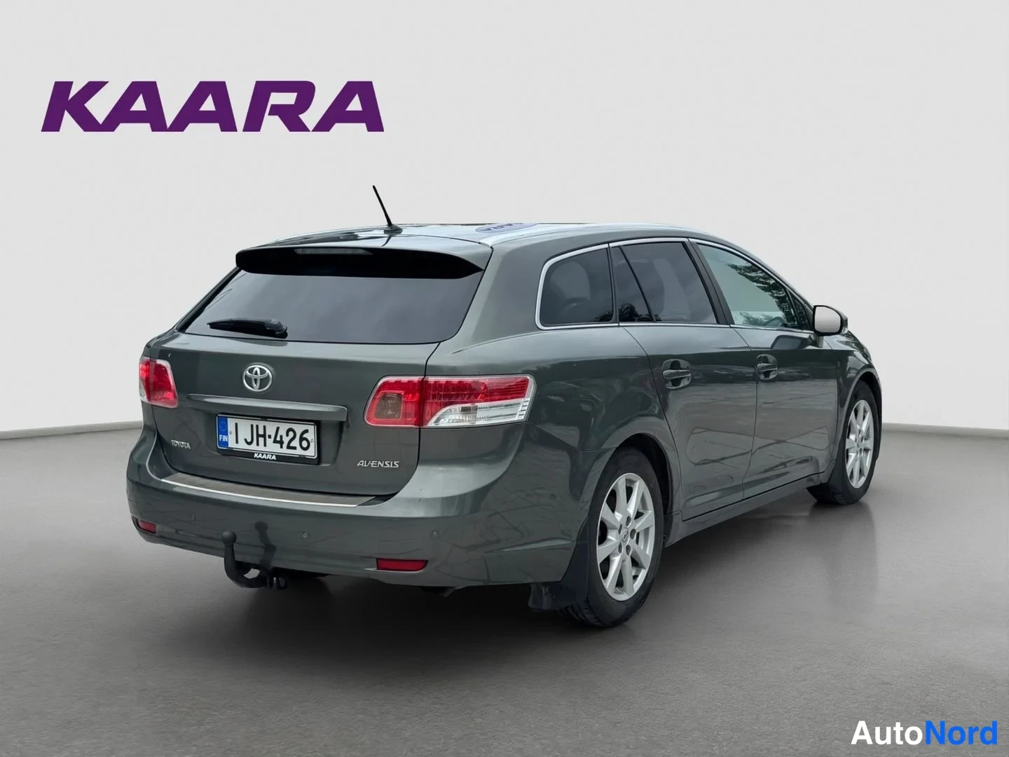 Takaviisto: Tummanharmaa Toyota Avensis -farmari takaviistosta, rekisteritunnus ja vetokoukku.