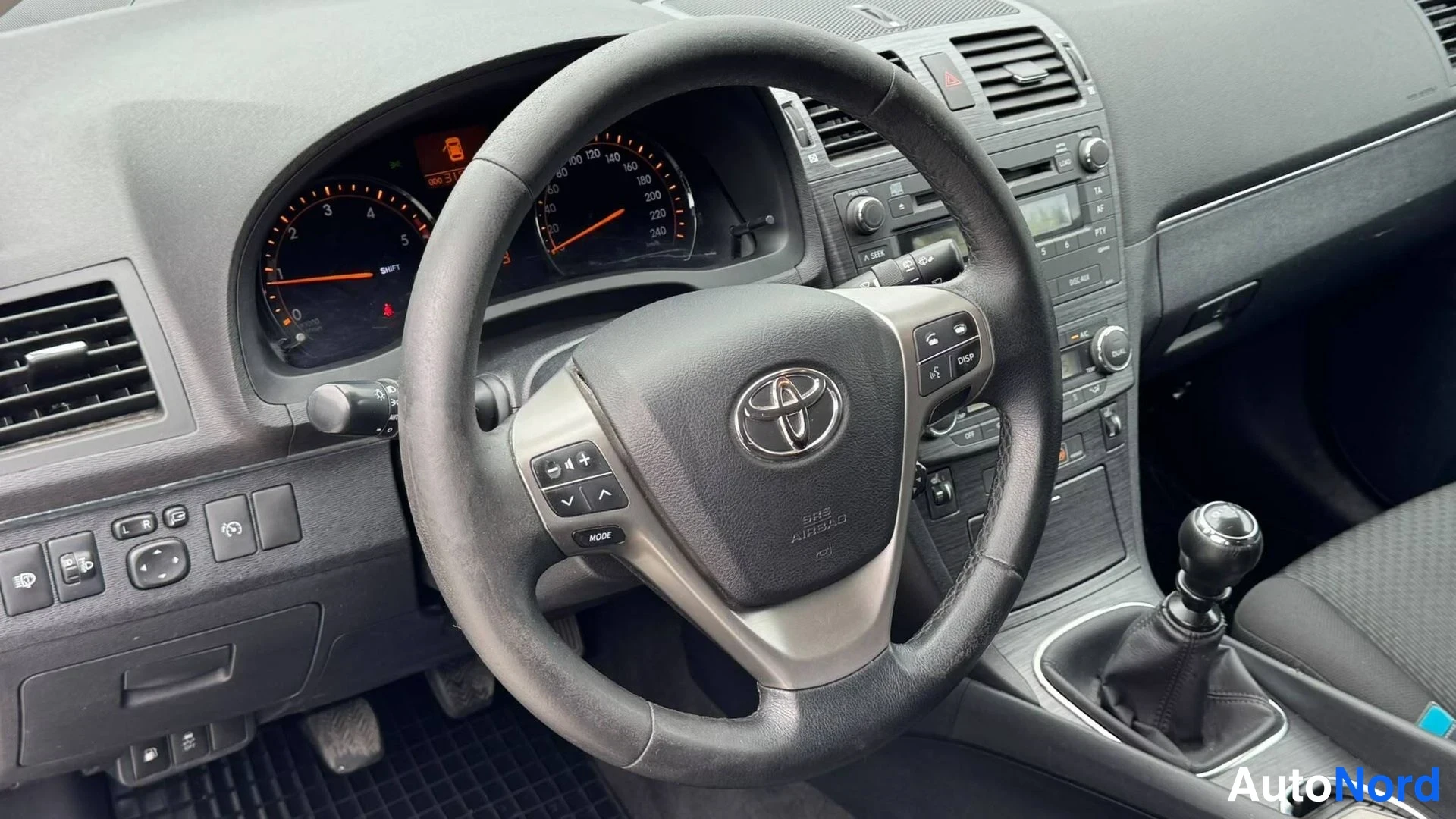 Muu: Toyota-merkki ohjauspyörässä, manuaalivaihto, kojelaudan mittarit ja vaihto-/käsijarrupainikkeet.