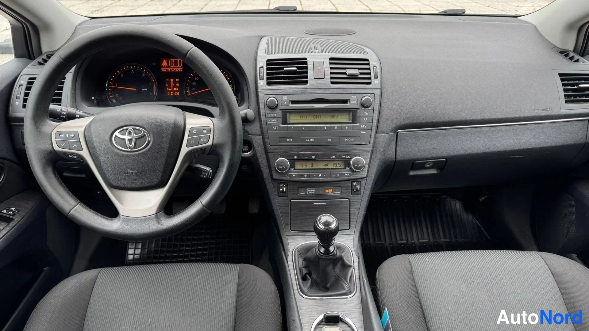 Muu: Ajonäkyvistä kuvattu ohjaamo: Toyota-ohjauspyörä, analogiset mittarit, audio-Cd-radio ja manuaalivaihteen keilakatkaisin näkyvät kojelaudan keskellä.