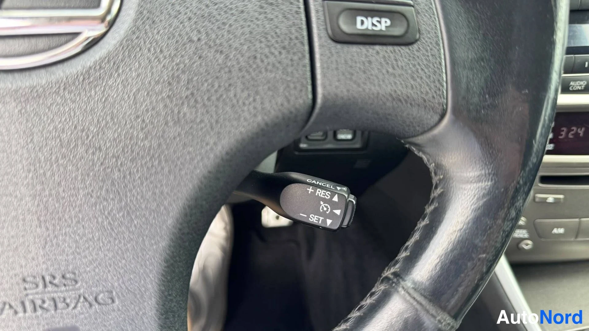 Muu: Rattitietotestin sijaan kuvassa ratin takainen vakionopeudensäädinsauva, jossa merkinnät +RES, -SET ja CANCEL; ratin SRS AIRBAG -teksti ja DISP-nappi.
