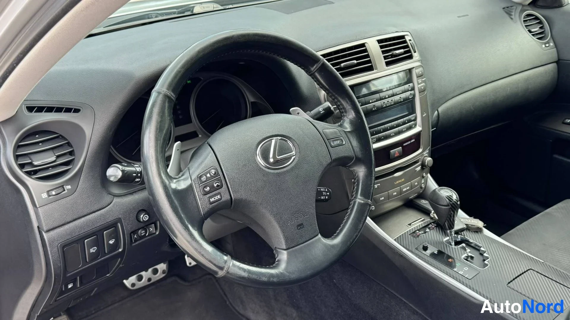 Etuviisto: Ohjaamon kuva: Lexus-merkkinen ohjauspyörä, monitoiminapit, radio ja vaihtaja.
