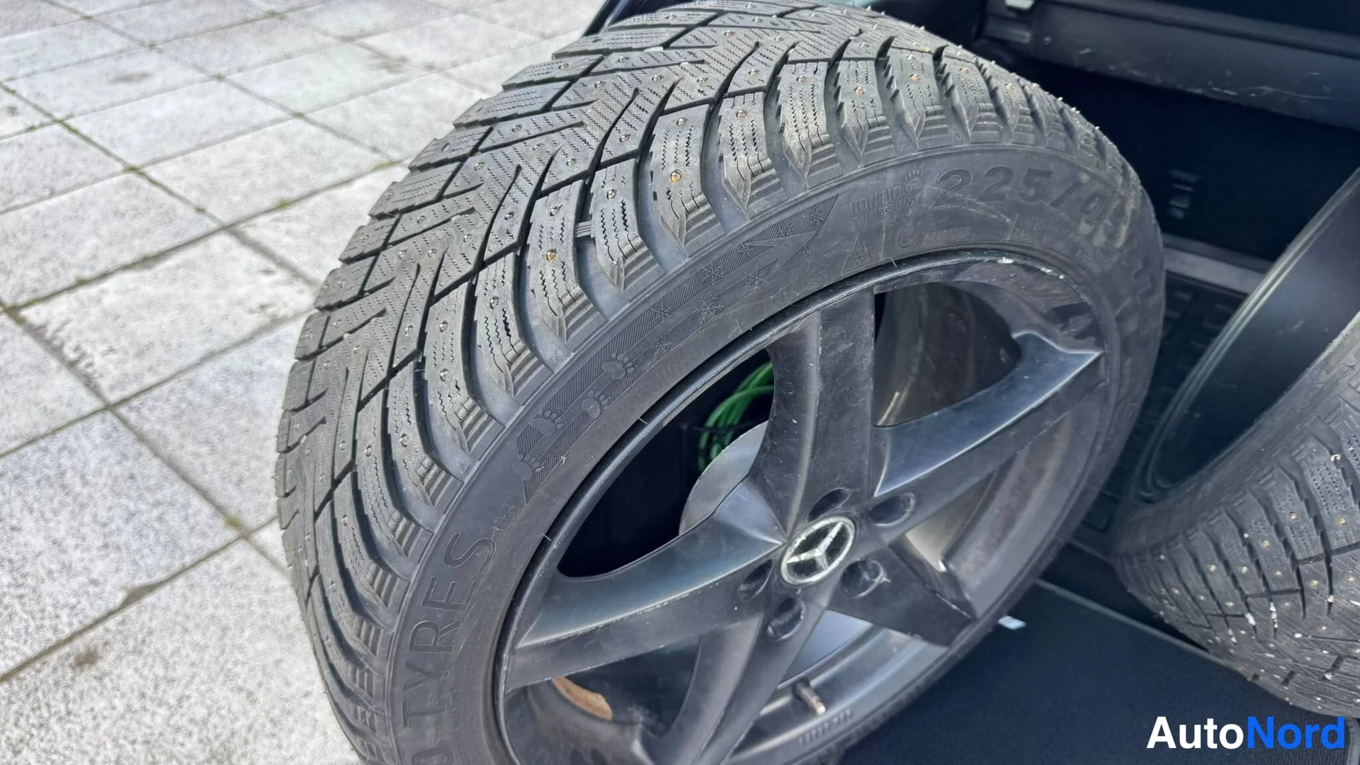 Yksityiskohta: Nastarenkainen varaovan kierros varastotilassa, Mercedes-tähdellä varustettu viisipuolainen vanne.