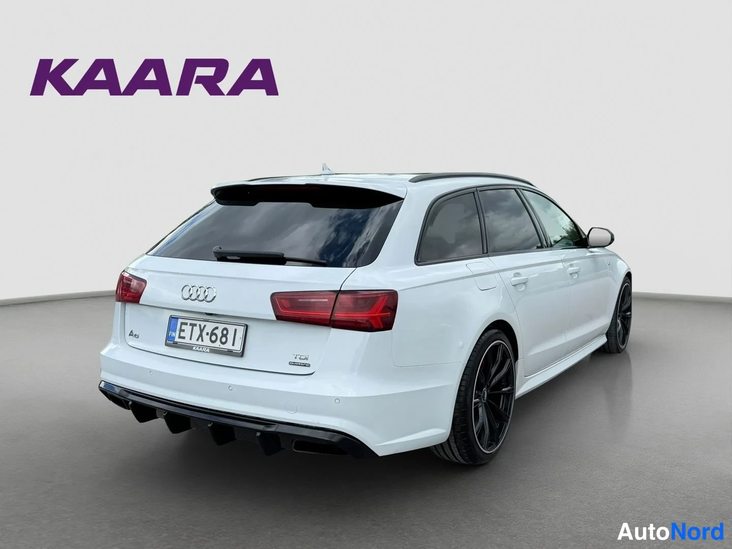 Takaviisto: Valkoinen Audi A6 Avant -farmari takakulmasta vasemmalle, musta diffuusori ja mustat vanteet, rekisteritunnus.