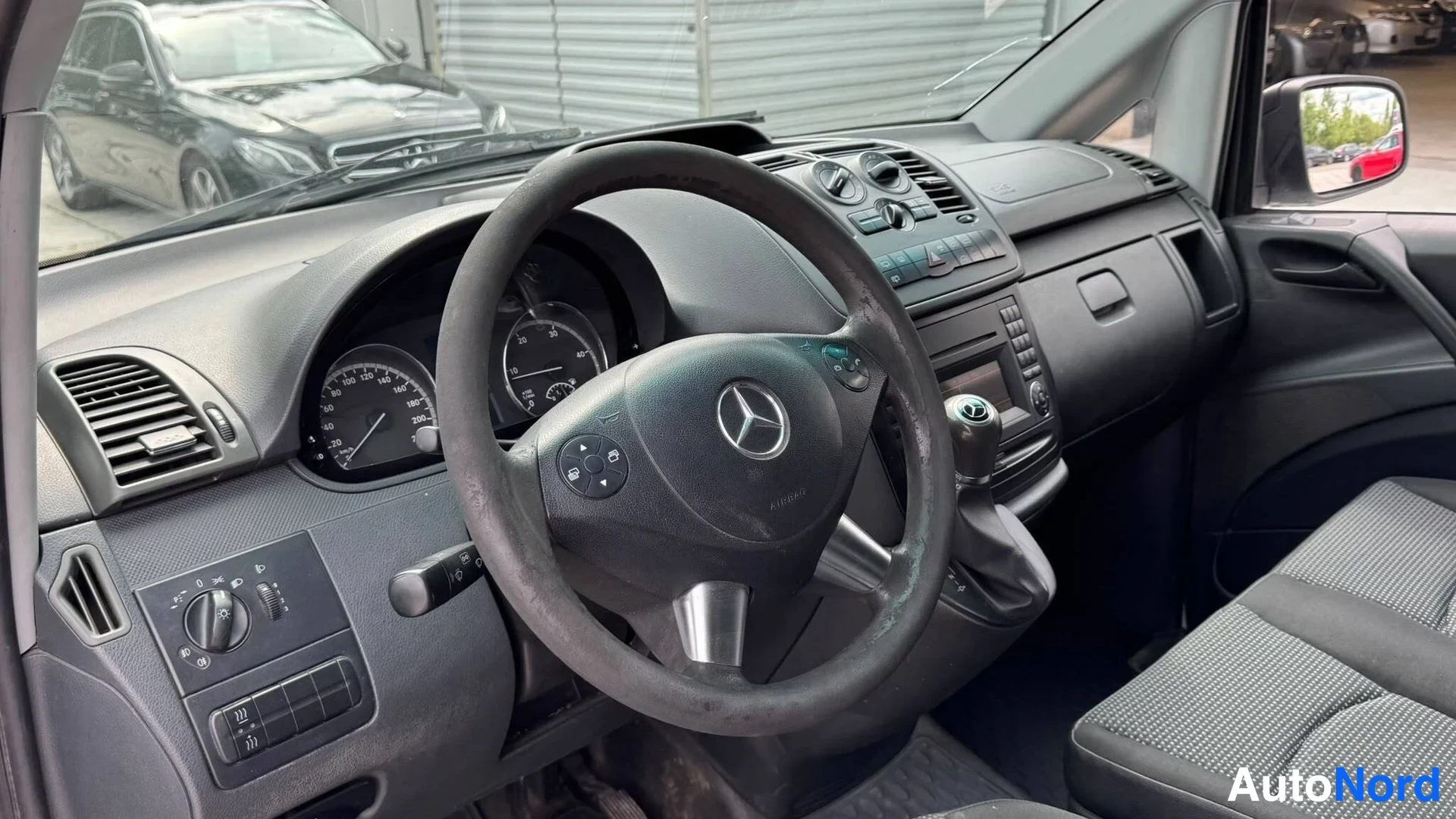 Yksityiskohta: Ohjaamon kuva: Mercedes-merkillä varustettu ratit ja mittaristo, keskikonsolin venttiilit ja manuaalivaihteen keila.