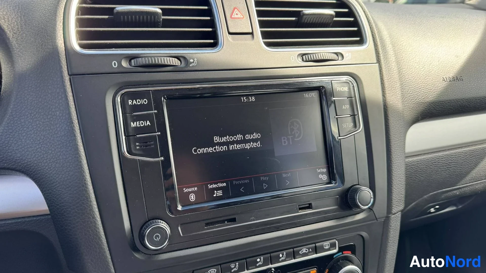 Yksityiskohta: Vaihtoauton kojelaudan infotainment-yksikkö näyttää Bluetooth-audioviestin 'Bluetooth audio Connection interrupted.', painikkeet RADIO, MEDIA, PHONE, APP ja SET