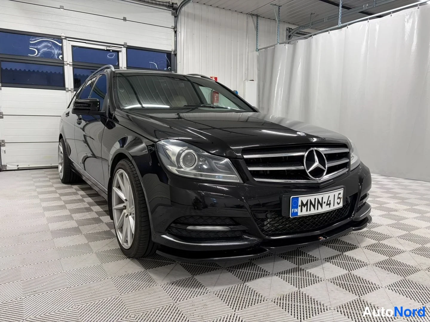 Etuviisto, nokka oikealle: Mercedes-Benz farmari mustana vinosta etu-oikealta, rekisteritunnus