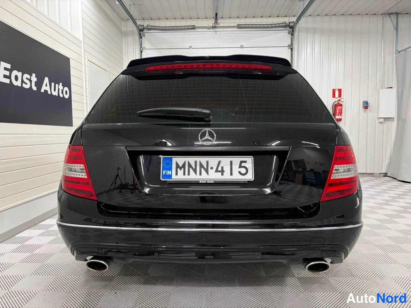 Takaa: Mustan Mercedes-Benz farmariaivan takapää suoraan takaa kuvattuna; rekisterikilpi ja kaksi pakoputkenpäätä.