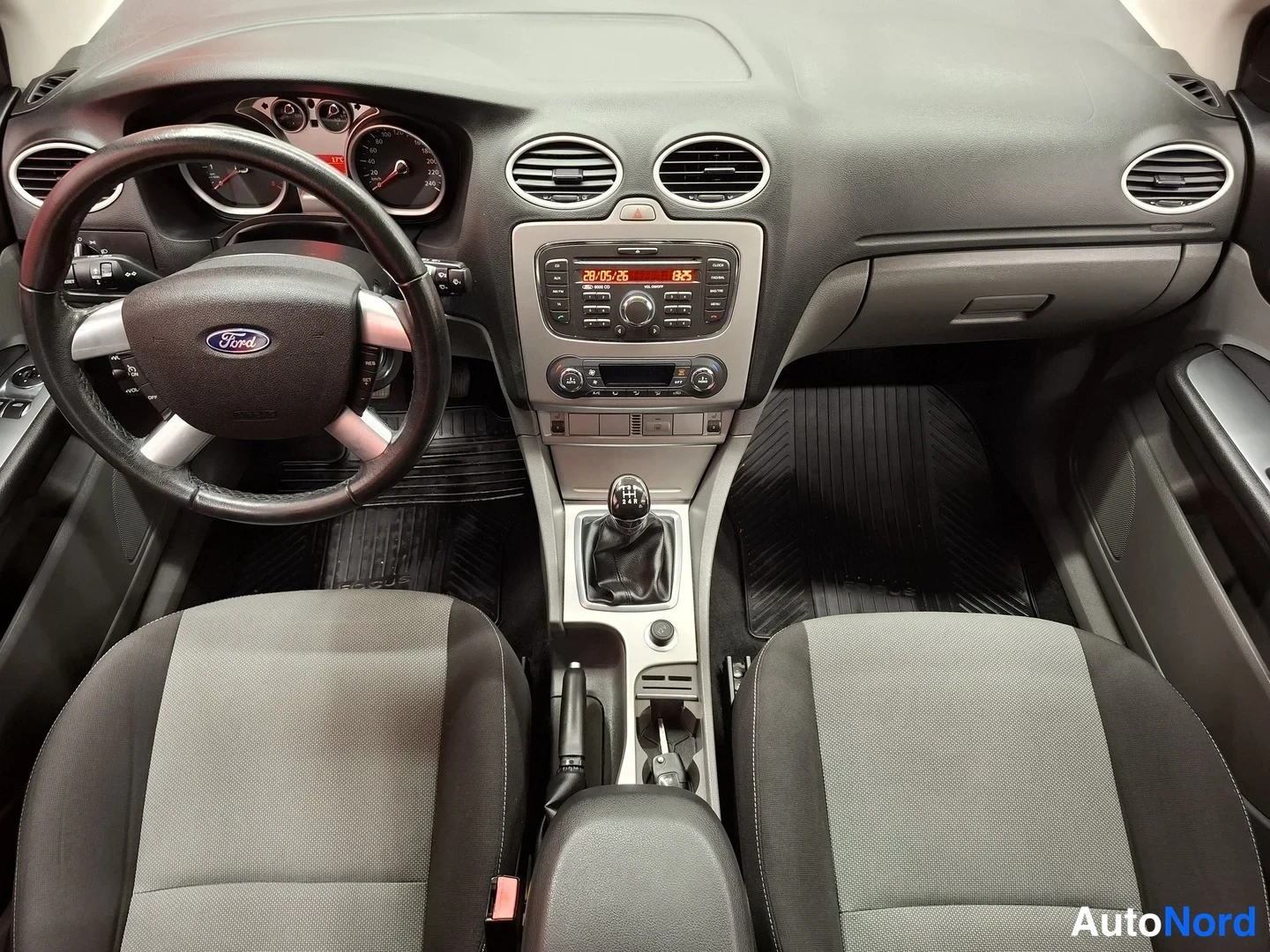 Muu: Ford Focusin ohjaamo edestä: Ford-merkillinen ohjauspyörä, analogiset mittarit, audiolaite näytöllä 20.05.25 / 8.5, viisipaikkainen istuinjärjestys ja manuaaliv