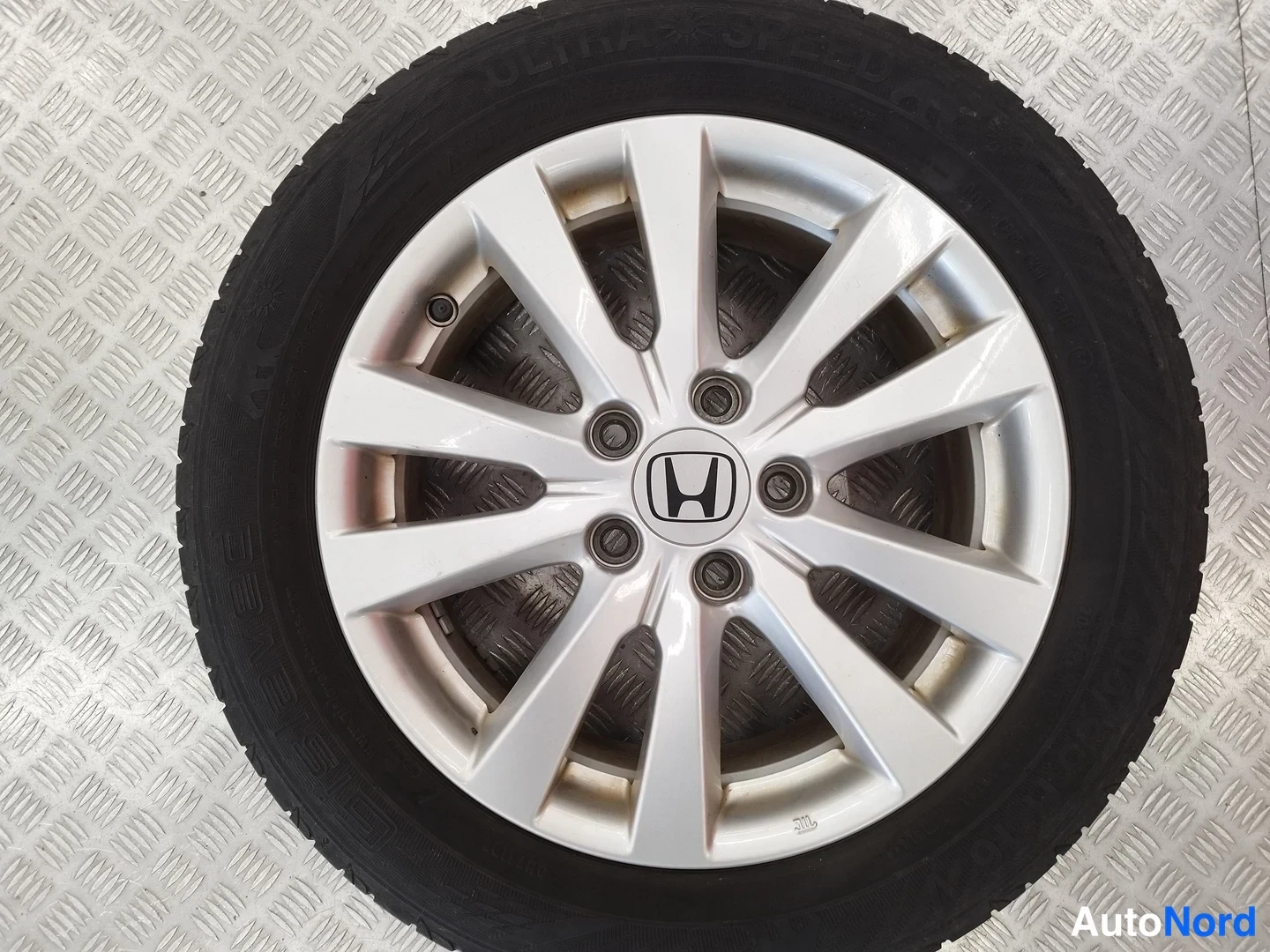 Sivulta: Honda-vanteen kulutuspinta ja runko hienolla raudoitteisella pinnalla, vanteen keskellä merkin H-logo; rengas vanteen ympärillä