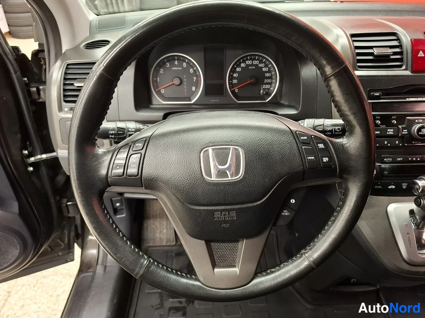 Muu: Honda CR-V:n ohjauspyörä ja kojelauta: H-merkki, nopeusmittari, kierroslukumittari ja radiopaneeli.