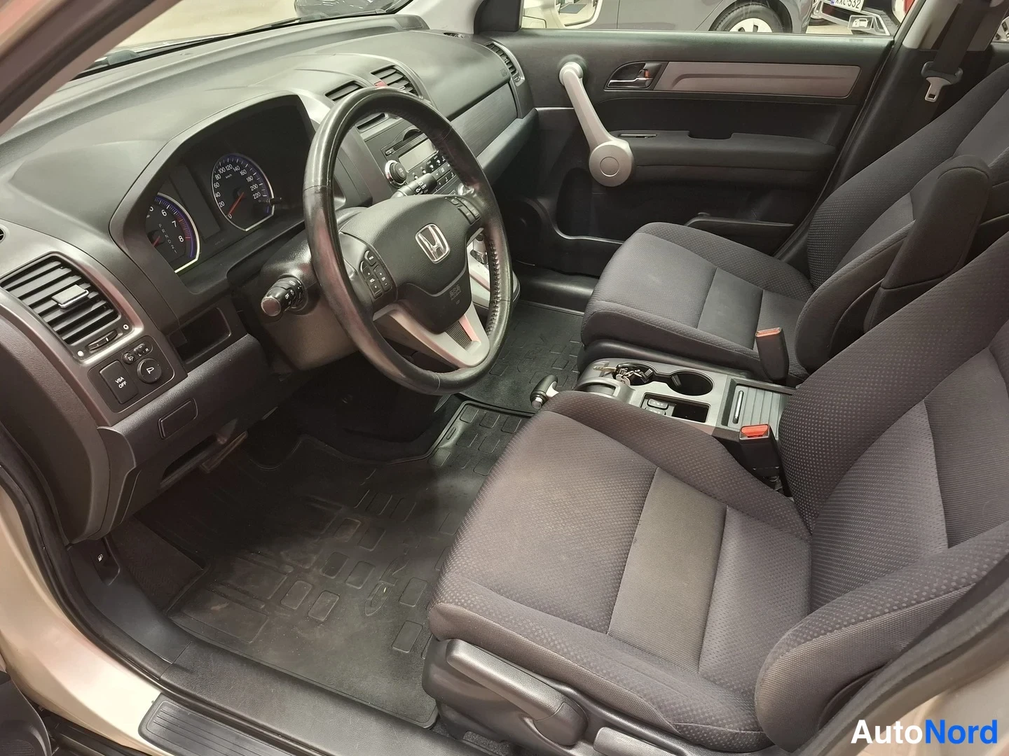 Muu: Auton sisätilat: Honda-ohjauspyörä, kojelauta ja harmaat kangasistuimet.