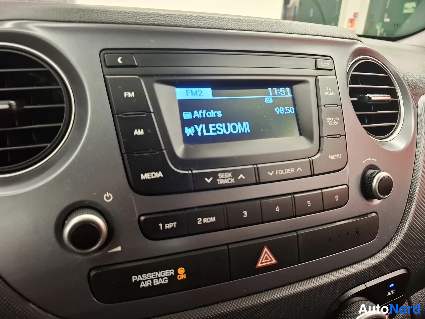 Muu: Kojelaudan radiopaneeli: näytöllä FM2, kanava 98,50 YLESUOMI, kellonaika 11:51. Painikkeita FM, AM, MEDIA, SEEK TRACK, FOLDER sekä numeronäppäimet 1–6.