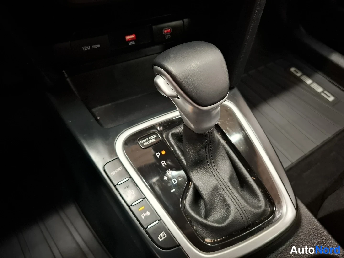 Yksityiskohta: Automaattivaihteen valitsin, jossa P, R, N ja D-asemat, SPORT-, drive mode- ja jarrupidikenappi sekä Ceed-merkitty lattiakokoluokitusmatto.