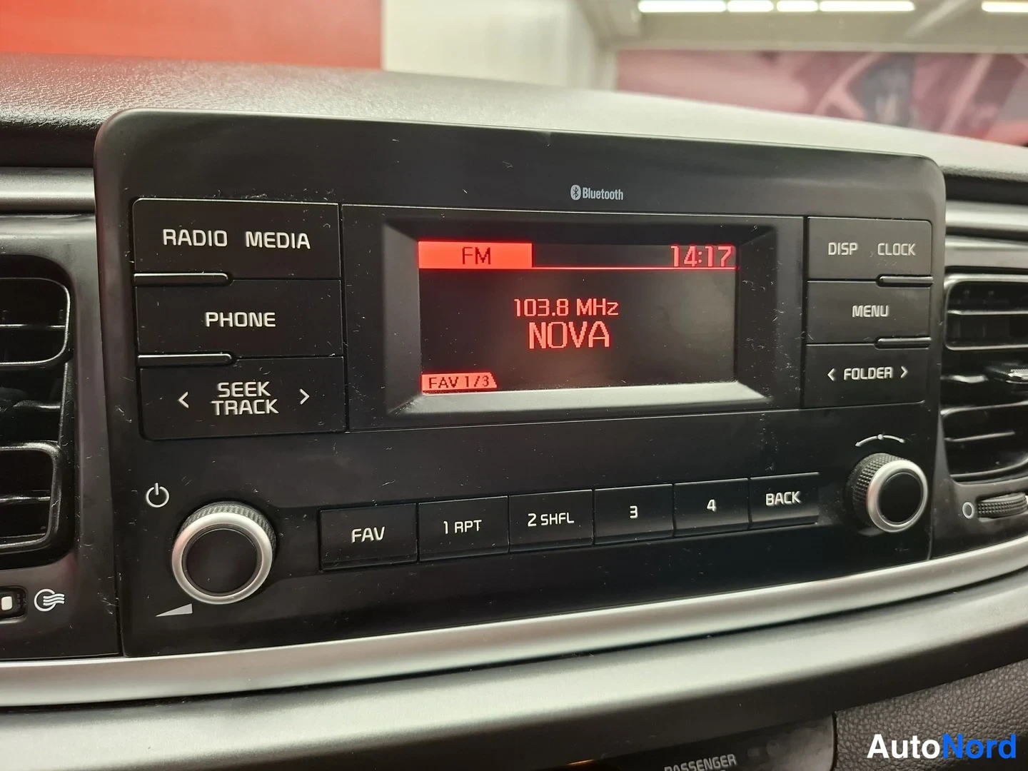 Yksityiskohta: Auton radio: näytössä FM 103.8 MHz NOVA, kellonaika 14:17, painikkeet RADIO MEDIA, PHONE ja Bluetooth-merkintä.