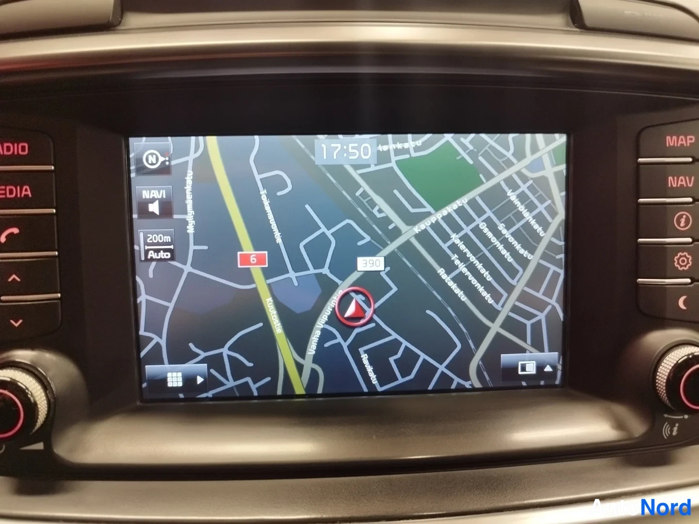 Yksityiskohta: Auton infotainment-näytön navigaatiokartta Helsingin kaduilla, kello 17:50, näytön reunoilla MAP-, NAV- ja asetuspainikkeet.