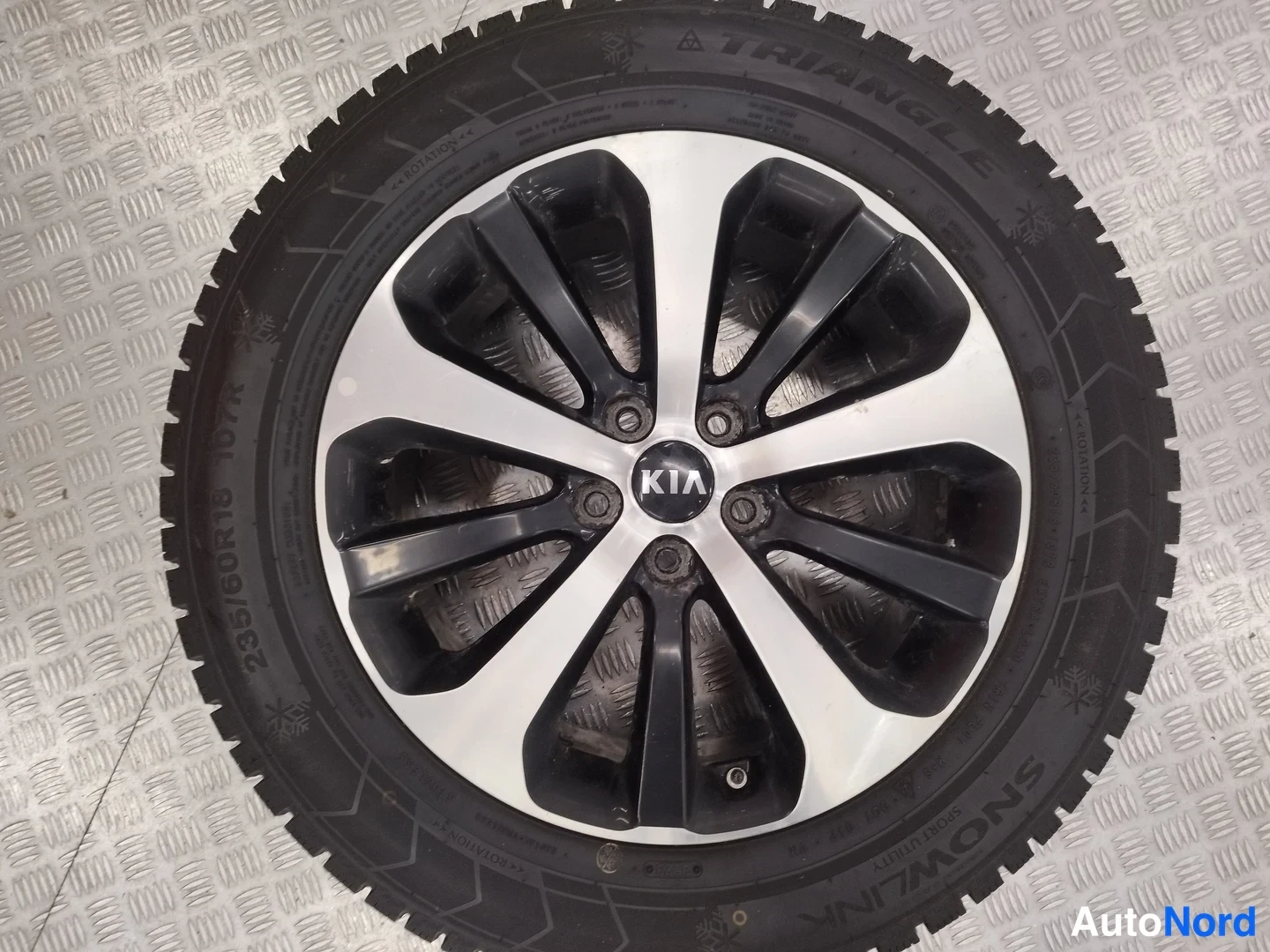 Yksityiskohta: Kia-alkuvanteessa oleva Triangle Snowlink-nastarengas, sivuseinässä lukee 235/60R18 107H.