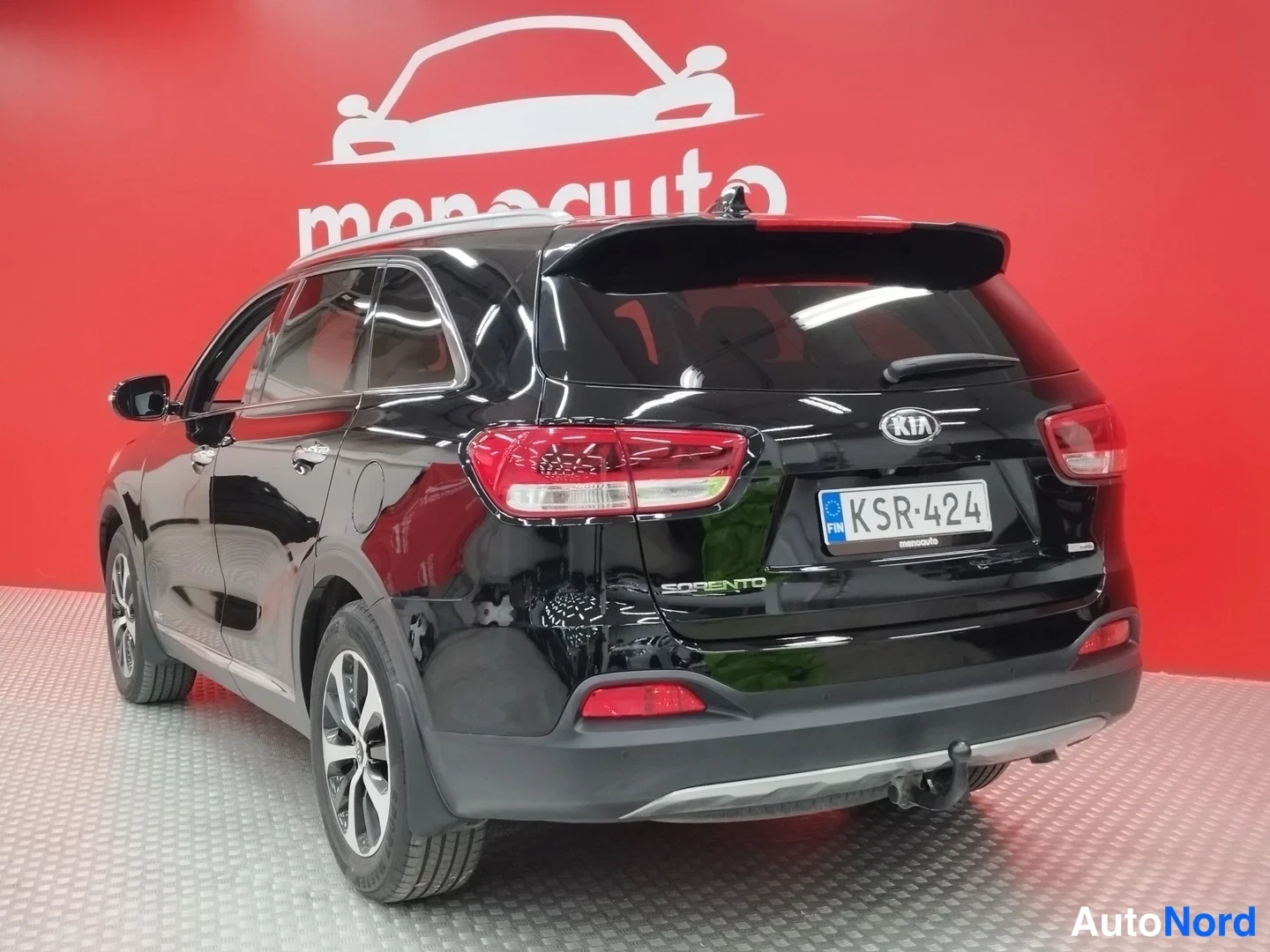 Takaviisto: Mustan Kia Sorenton takakulmanäkymä rekisterikilvellä punaisella taustalla.