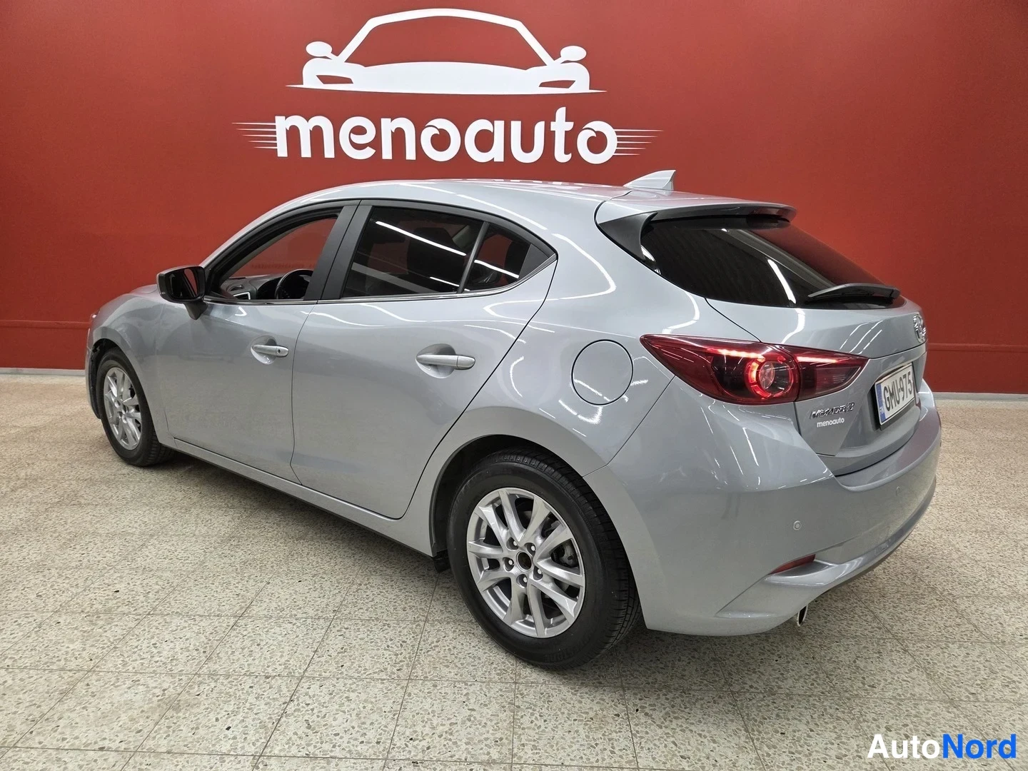 Takaviisto: Hopeanväräinen Mazda 3 -viistoperä takaa kolmannenvälin kulmakuvassa, takavalot ja takaluukku näkyvissä.