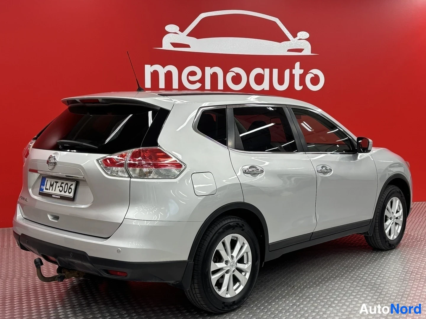 Takaviisto: Hopea Nissan X-Trail takaa vasemmalta kolmasosan kuvassa punaisella taustalla, rekisterikilpi.
