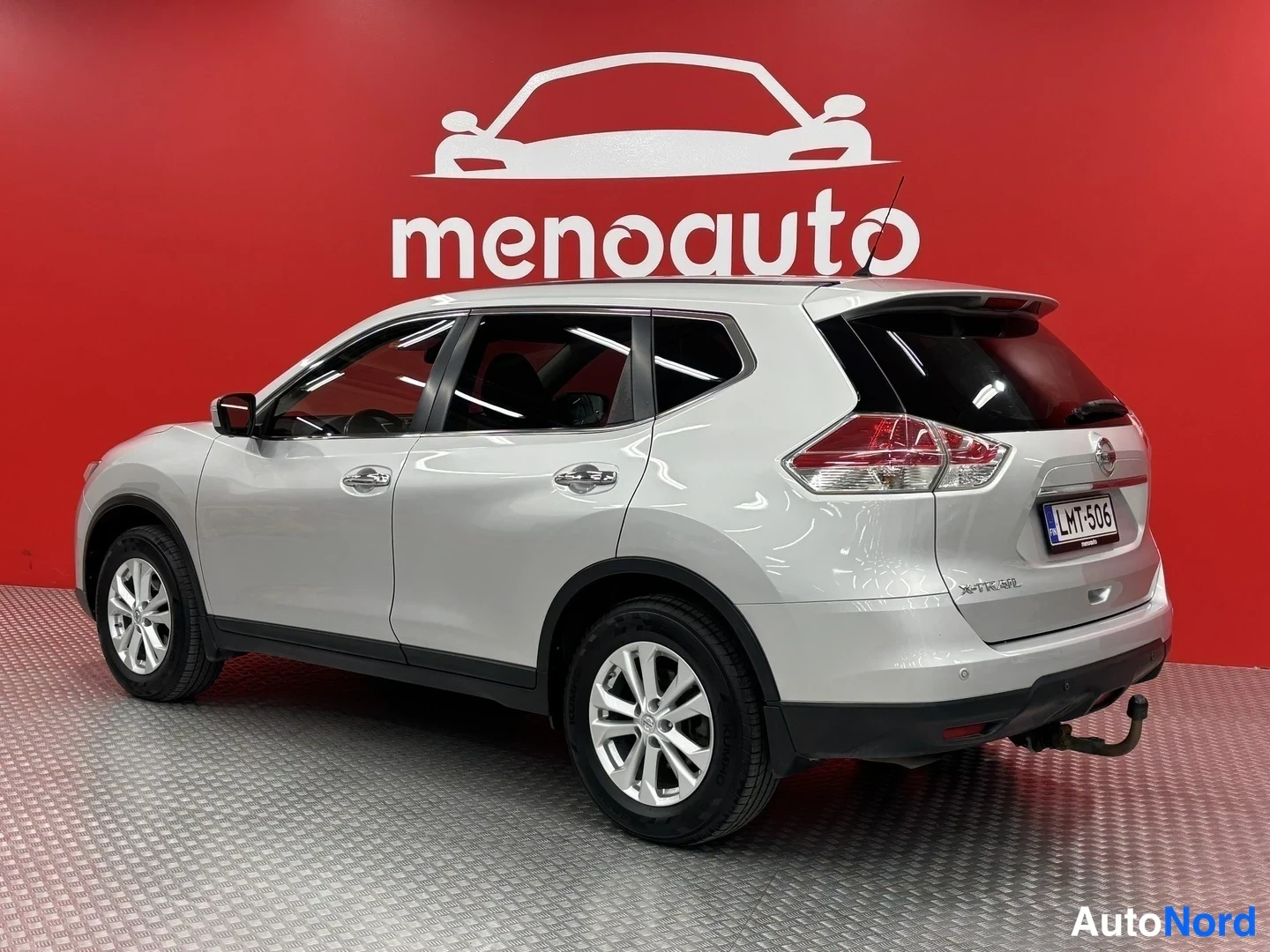 Takaviisto: Hopeanvärinen Nissan X-Trail takakulmasta, takapaneeli, takavalot ja vetokoukku näkyvissä, rekisteritunnus.