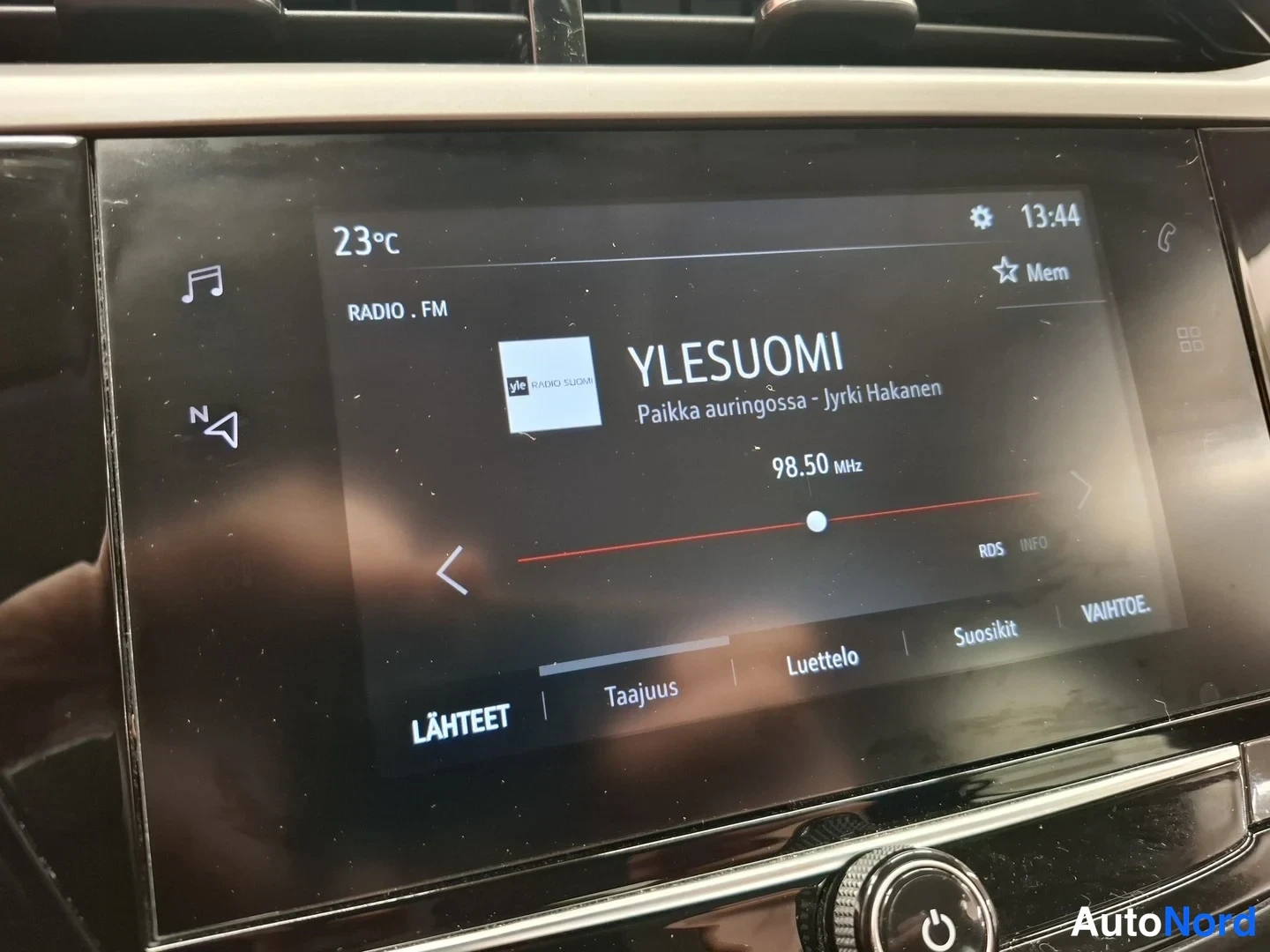 Muu: Auton infotainment-näyttö radioasemalla YLESUOMI 98.50 MHz, kellonaika 13:44.