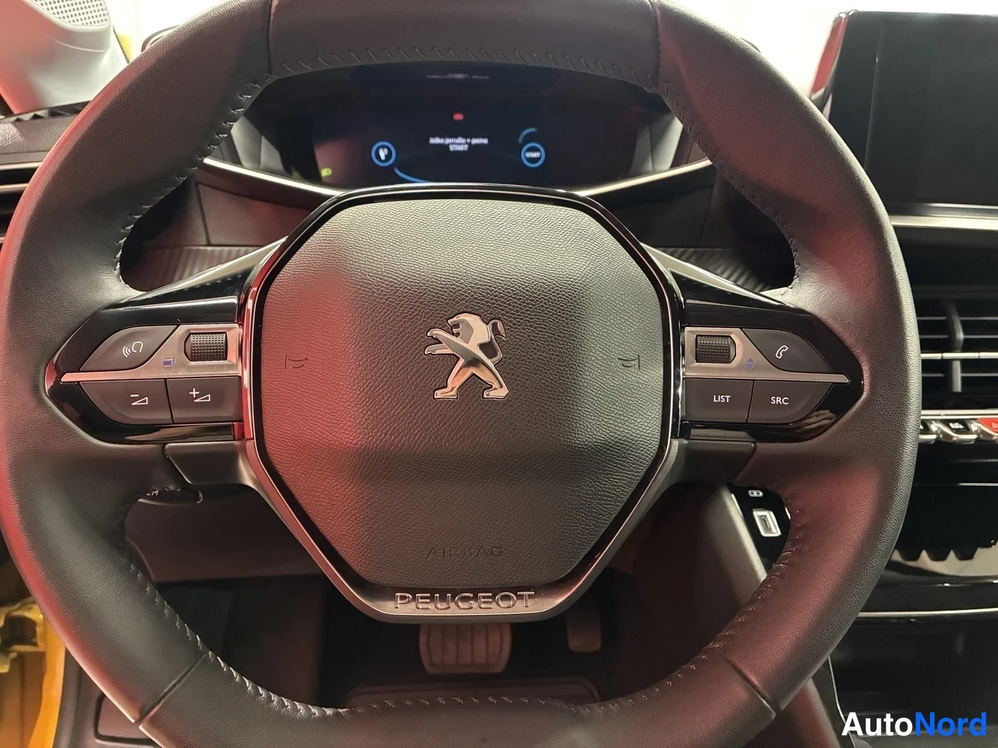 Muu: Peugeot-ohjauspyörä, jossa lion-tunnus ja monitoiminäppäimet, kojelautanäyttö taustalla.