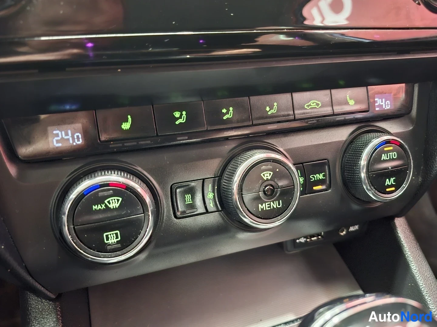 Muu: Auton ilmastointipaneeli, jossa näkyy lämpötila 24.0, AUTO- ja A/C-napit, SYNC-toiminto ja lämmitettävien istuinten painikkeet.