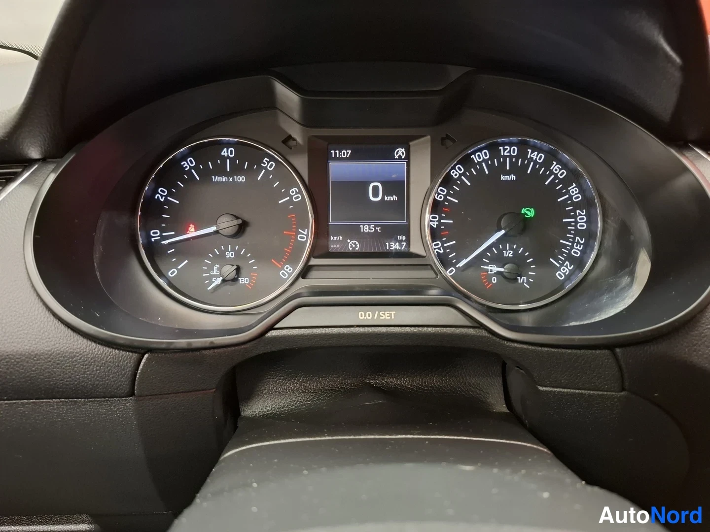 Muu: Autojen mittaristo: takamittari ja nopeusmittari, keskellä näyttö jossa 0 km/h, kello 11:07 ja matka 134,7.