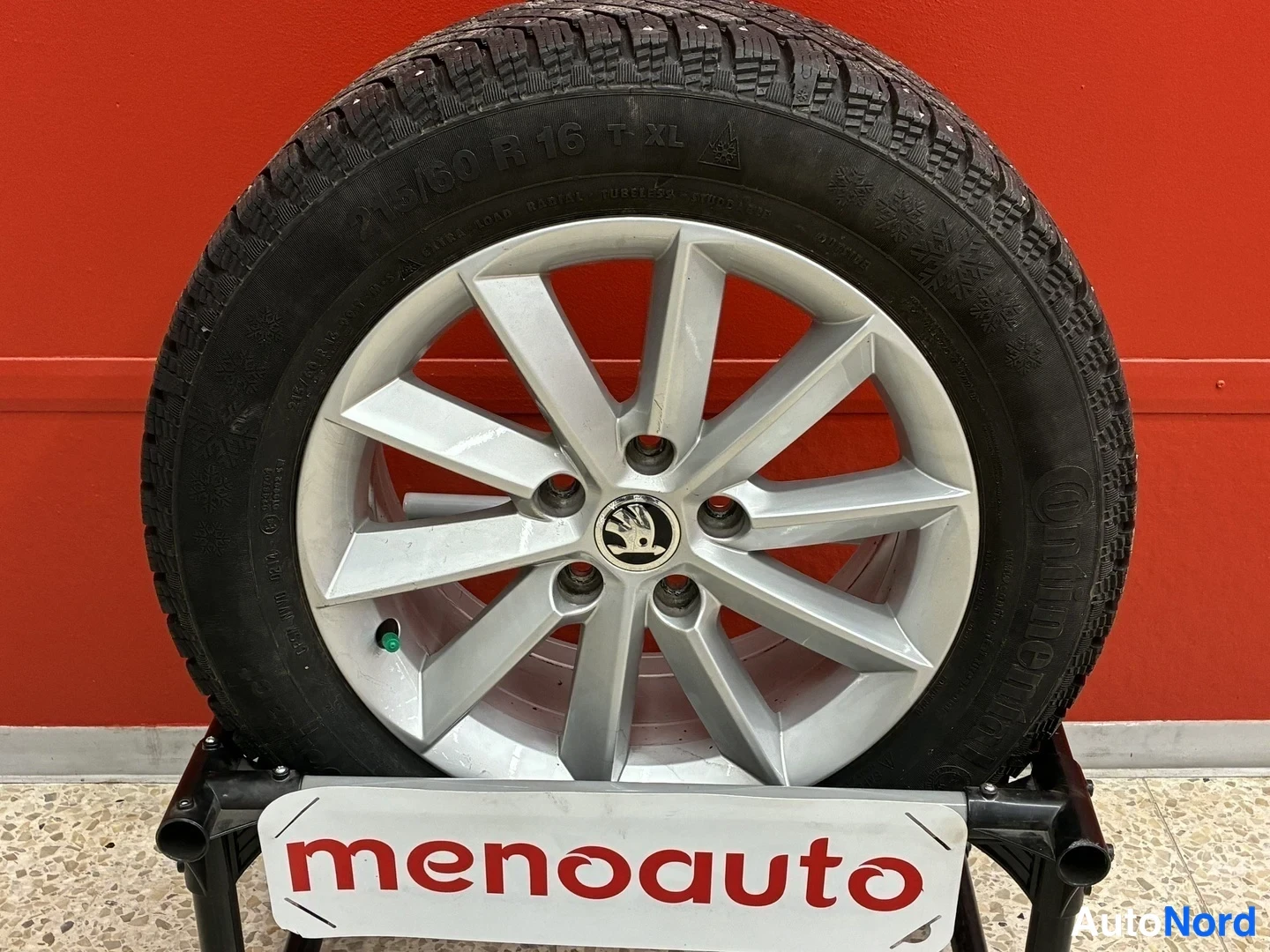 Muu: Hopeaväriinen alumiinivannas, Škoda-logo keskiössä, hiertolaatta, Continental-nastatyre 215/60 R 16, talvitaksite telineessä ja menoauto-kyltin edessä, punainen