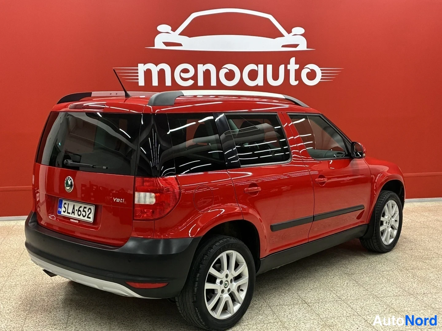 Takaviisto: Punainen Skoda Yeti takakulmasta vasemmalta, rekisteritunnus, taustalla punainen menoauto-mainosseina.