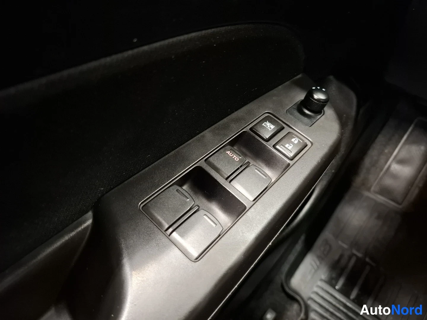 Muu: Auton oven sisäpaneeli, jossa ikkunankäsittelijät AUTO-merkinnällä, peilin säätönuppi ja lukituspainikkeet.