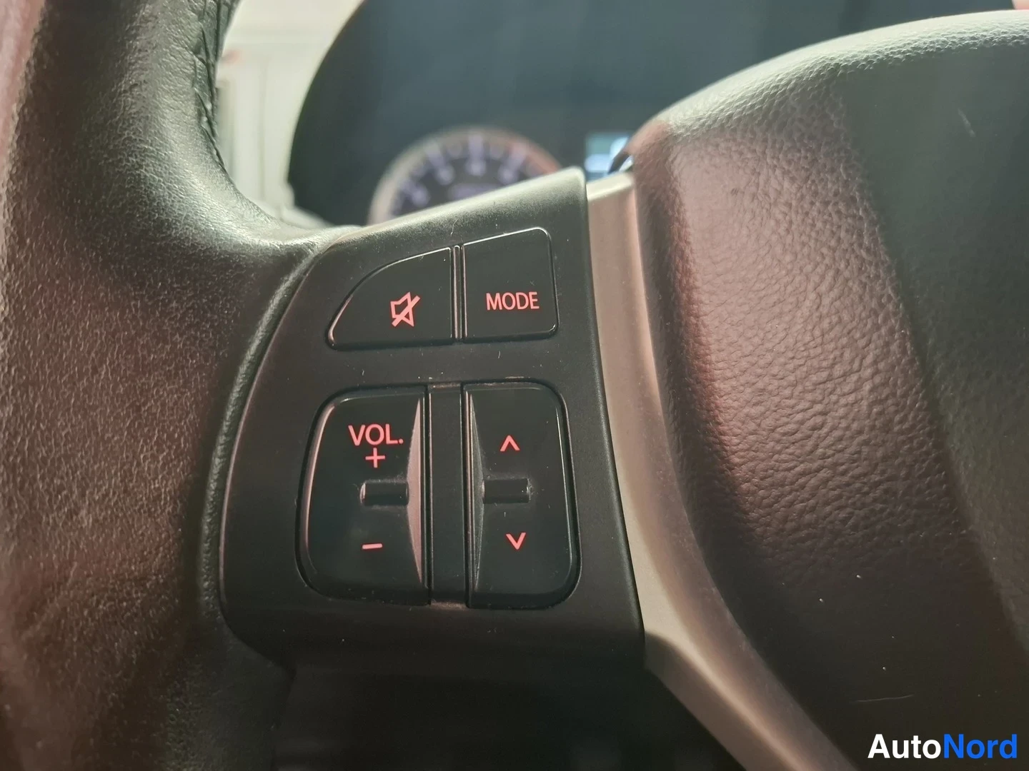 Yksityiskohta: Il volante ha i tasti audio sul lato sinistro, con etichette MODE, VOL. +, − e frecce su e giù.
