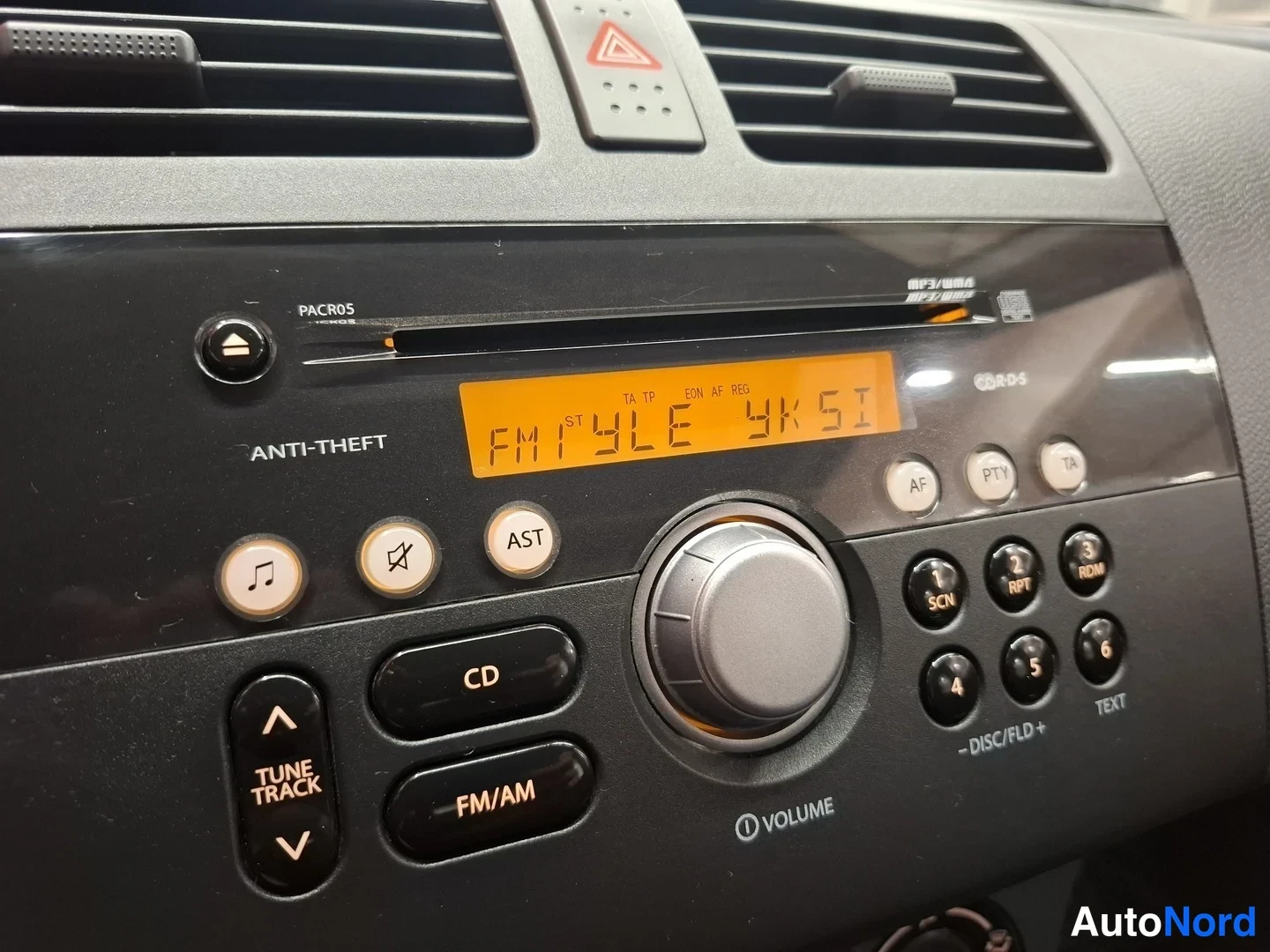 Yksityiskohta: Radio-CD-soitin, näyttö tekstillä FM1 YLE YKSI, painikkeet CD, FM/AM, AST, AF, PTY, TA.